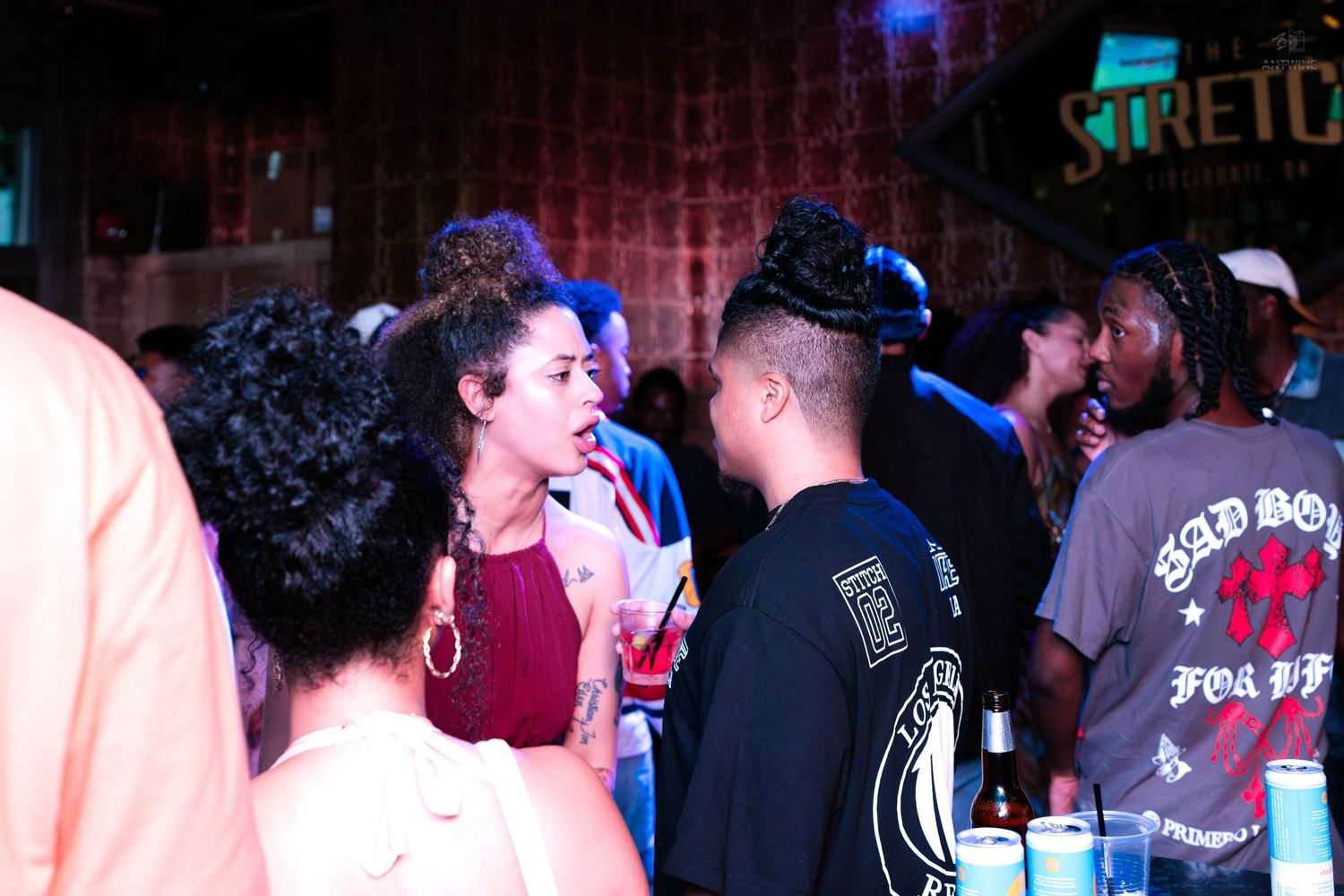 People socializing and drinking near a bar at a lively nightclub event.