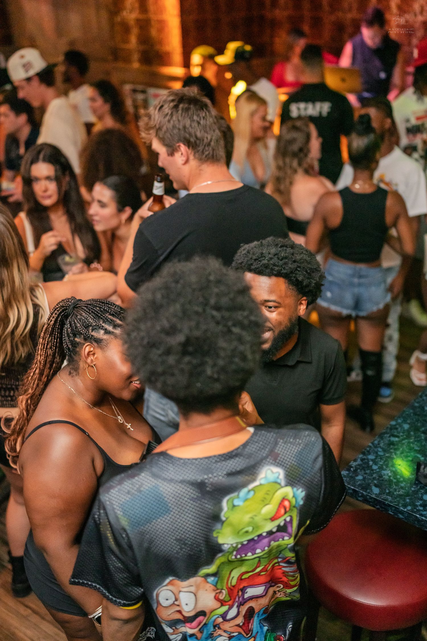 Diverse group of friends socializing and laughing together at a lively crowded bar event.