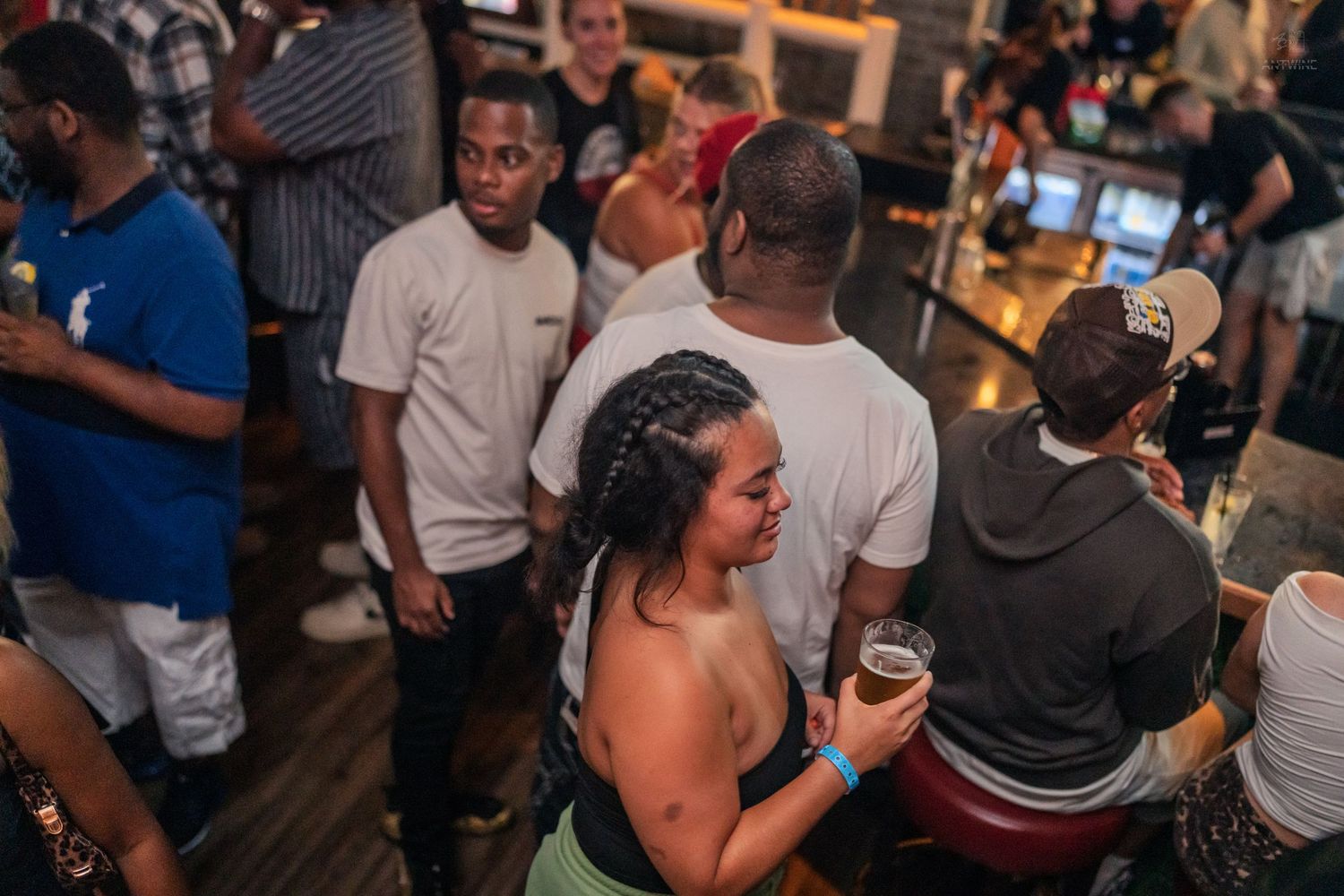 Diverse group of partygoers socializing at a busy indoor bar and nightclub.