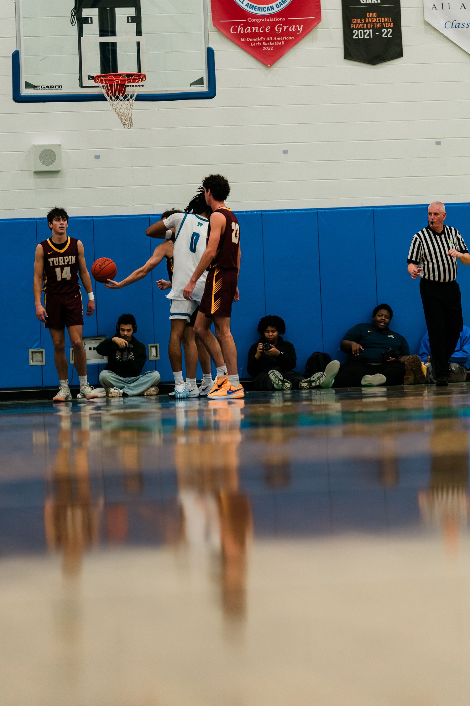 High school basketball player #0 receives a pass near the free throw line during a game.