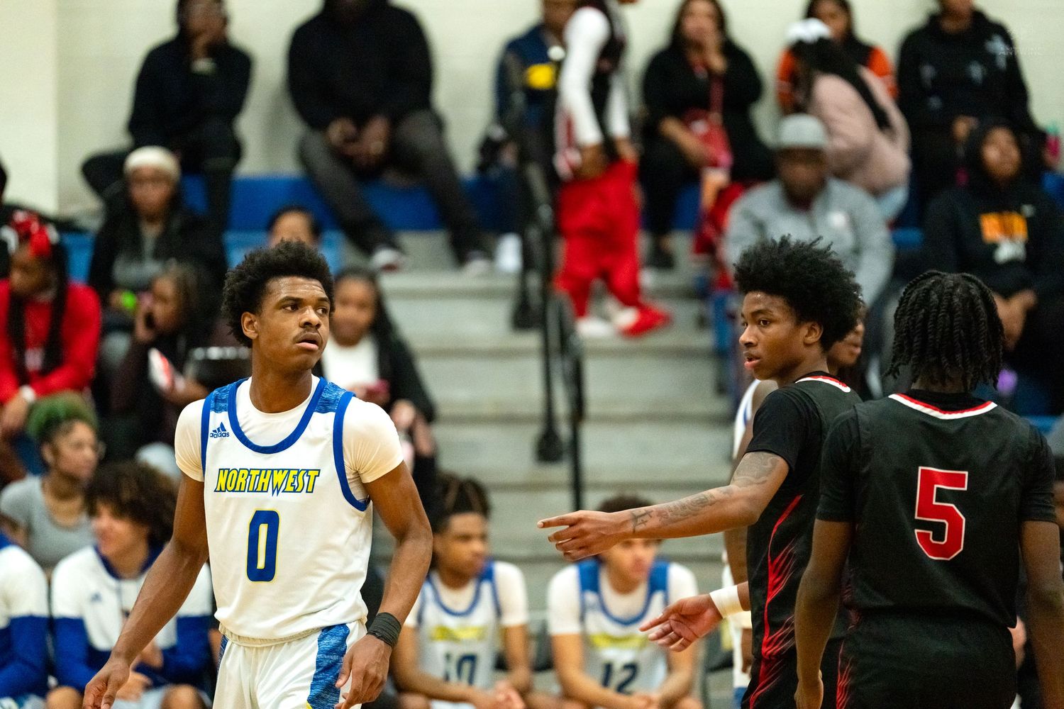 Knights player #0 in blue uniform faces opponents during high school basketball game.