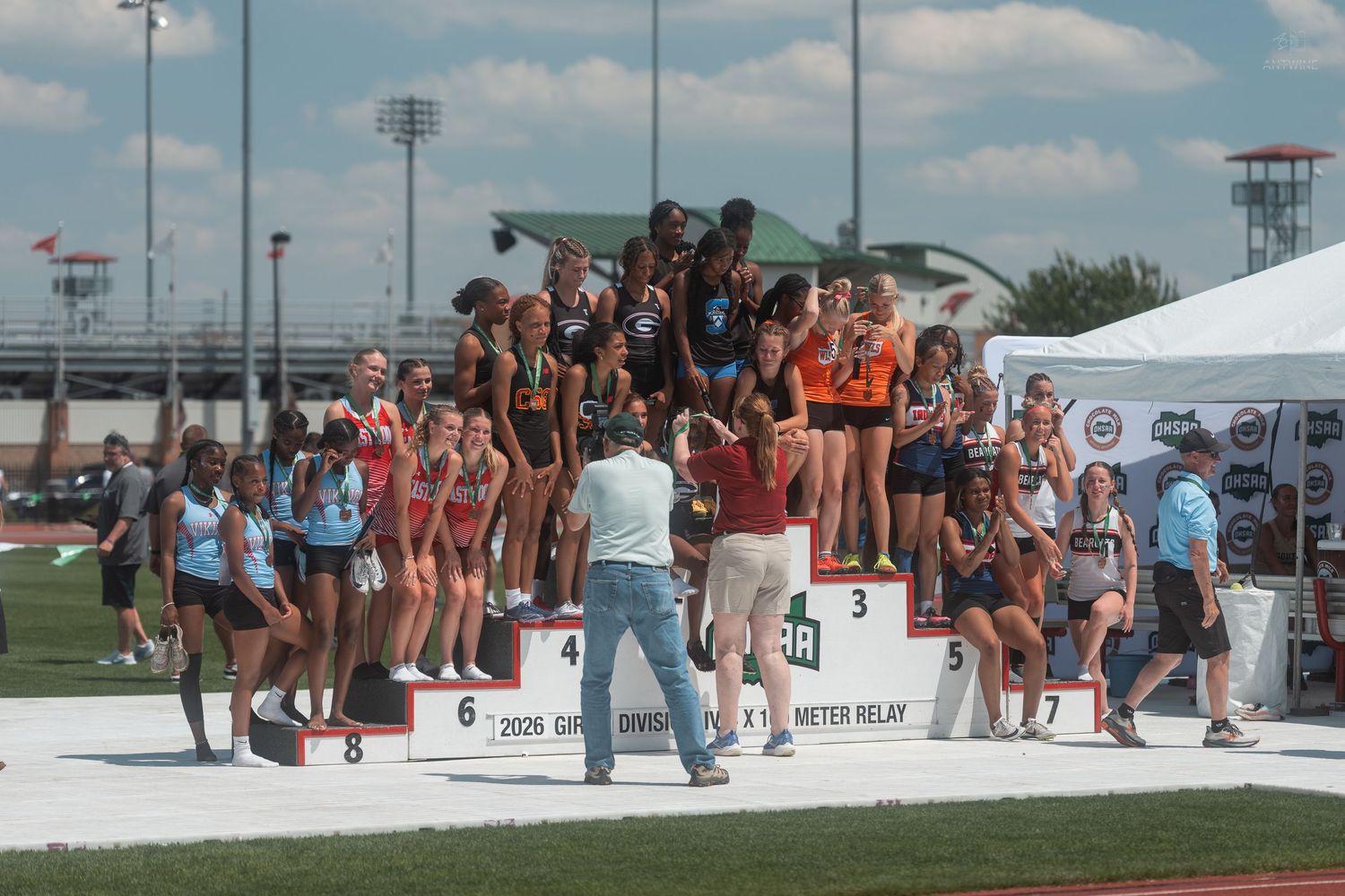 Female relay teams celebrating on awards podium at OHSAA Girls Division IV 4x100 Meter Relay championship.