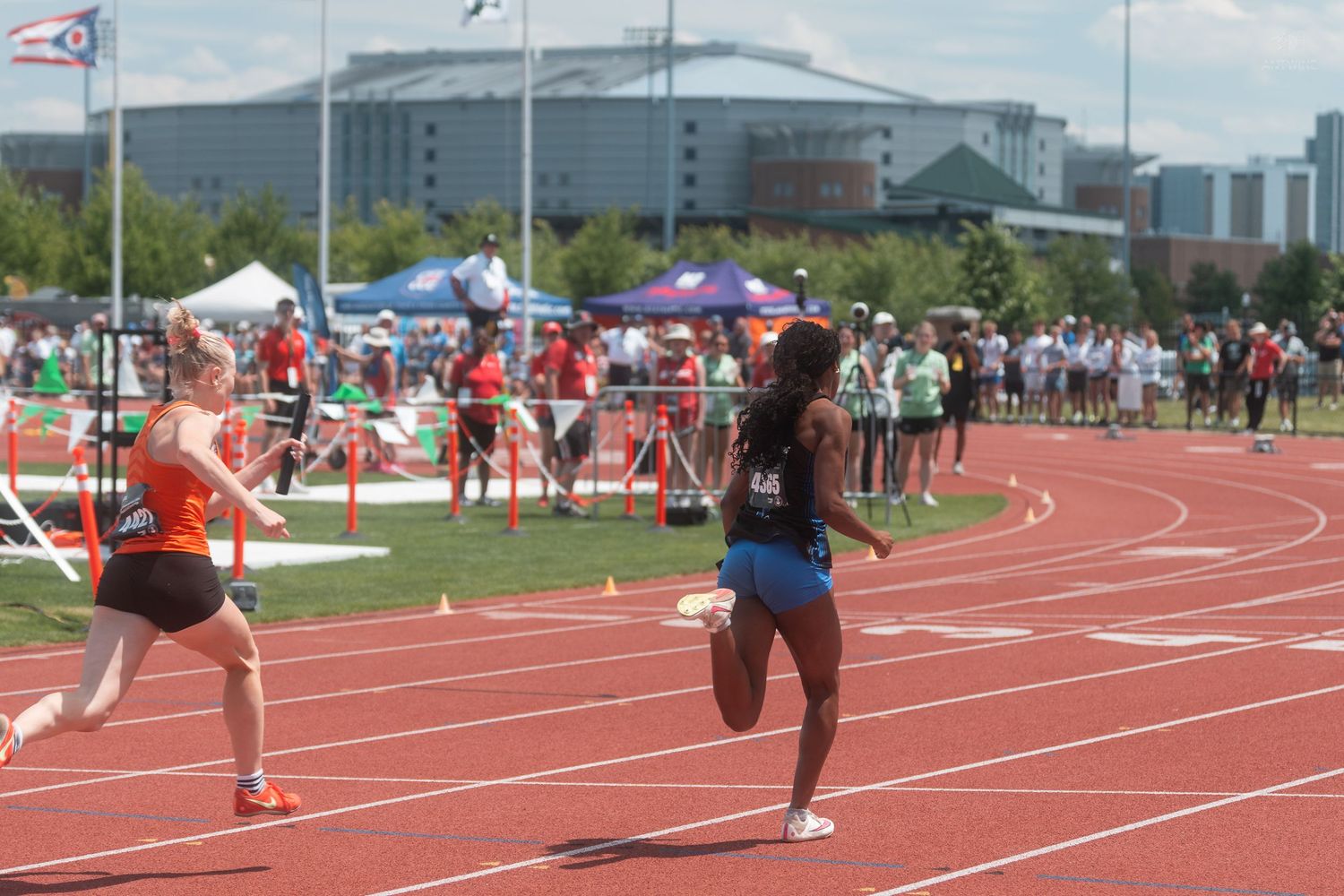 Female runners compete in a track race at an OHSAA high school athletics championship event outdoors.