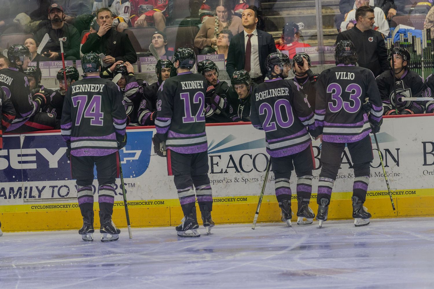 Purple-uniformed hockey team lines up on ice featuring players numbered 74, 12, 20, and 33.