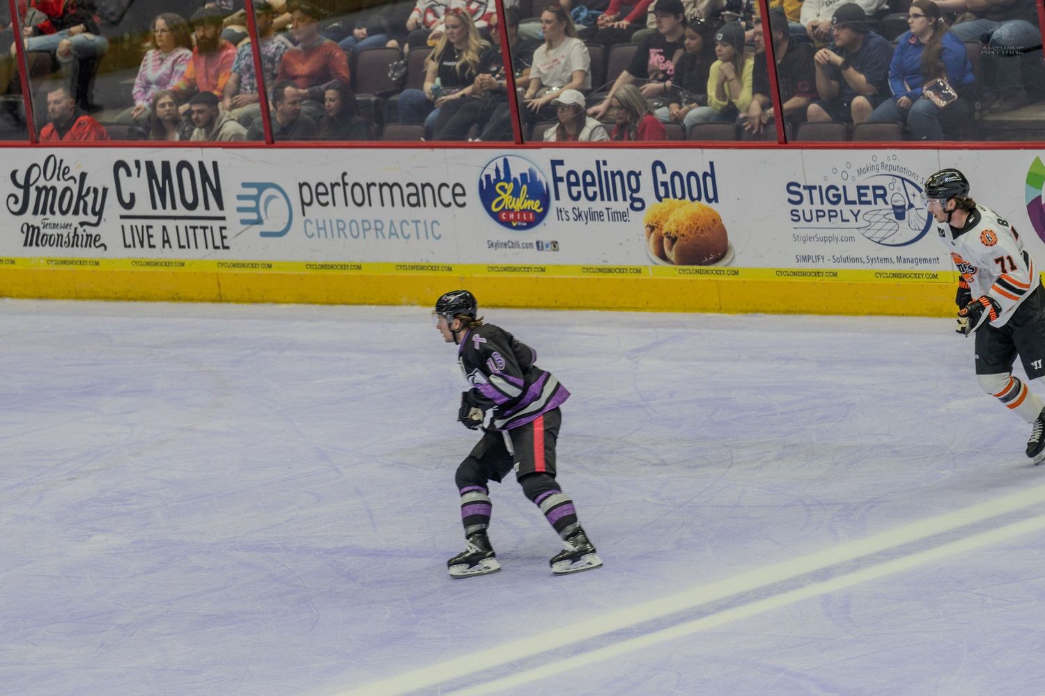 Hockey player in dark uniform skates with the puck during a game at Heritage Bank Center arena.