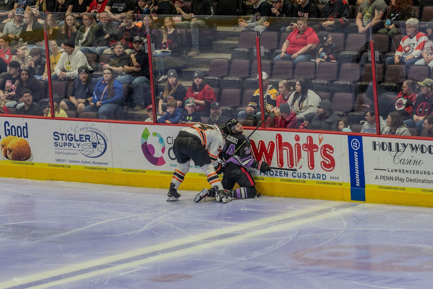 Two hockey players battle along the boards during a competitive ice hockey game.