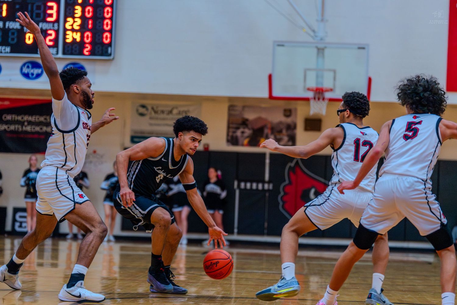 Lakota East player #0 dribbles through defenders during a high school basketball game.