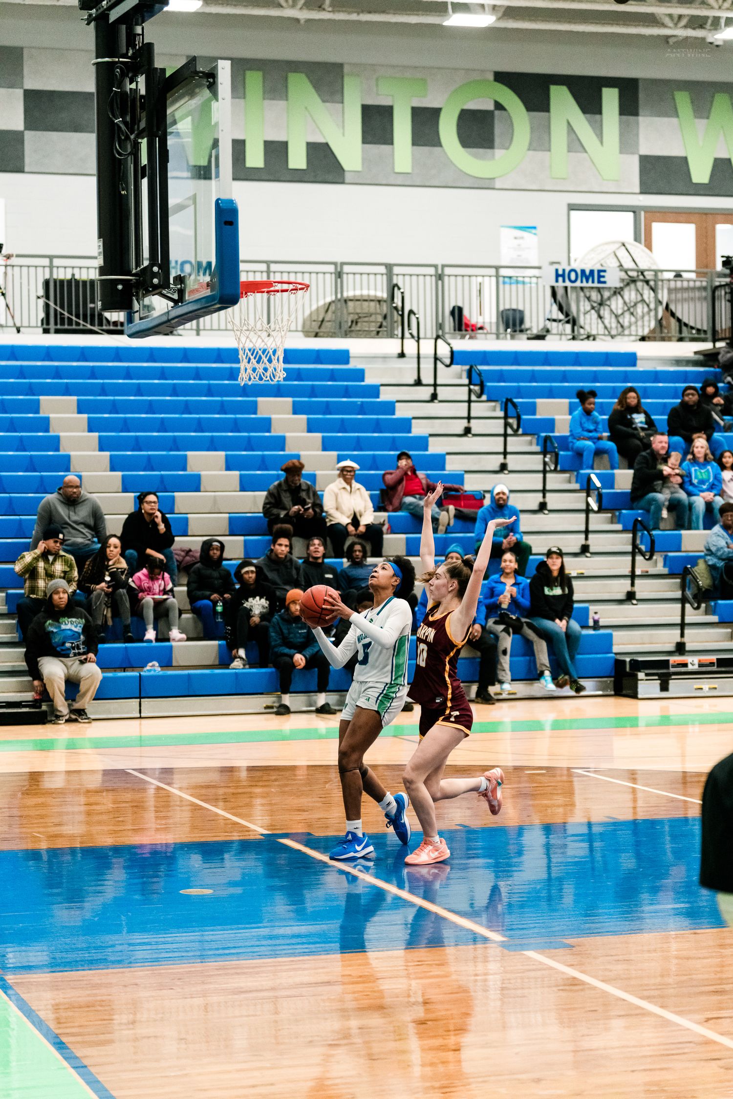 A Warriors girls basketball player drives to the basket past a Turpin defender in a high school game.