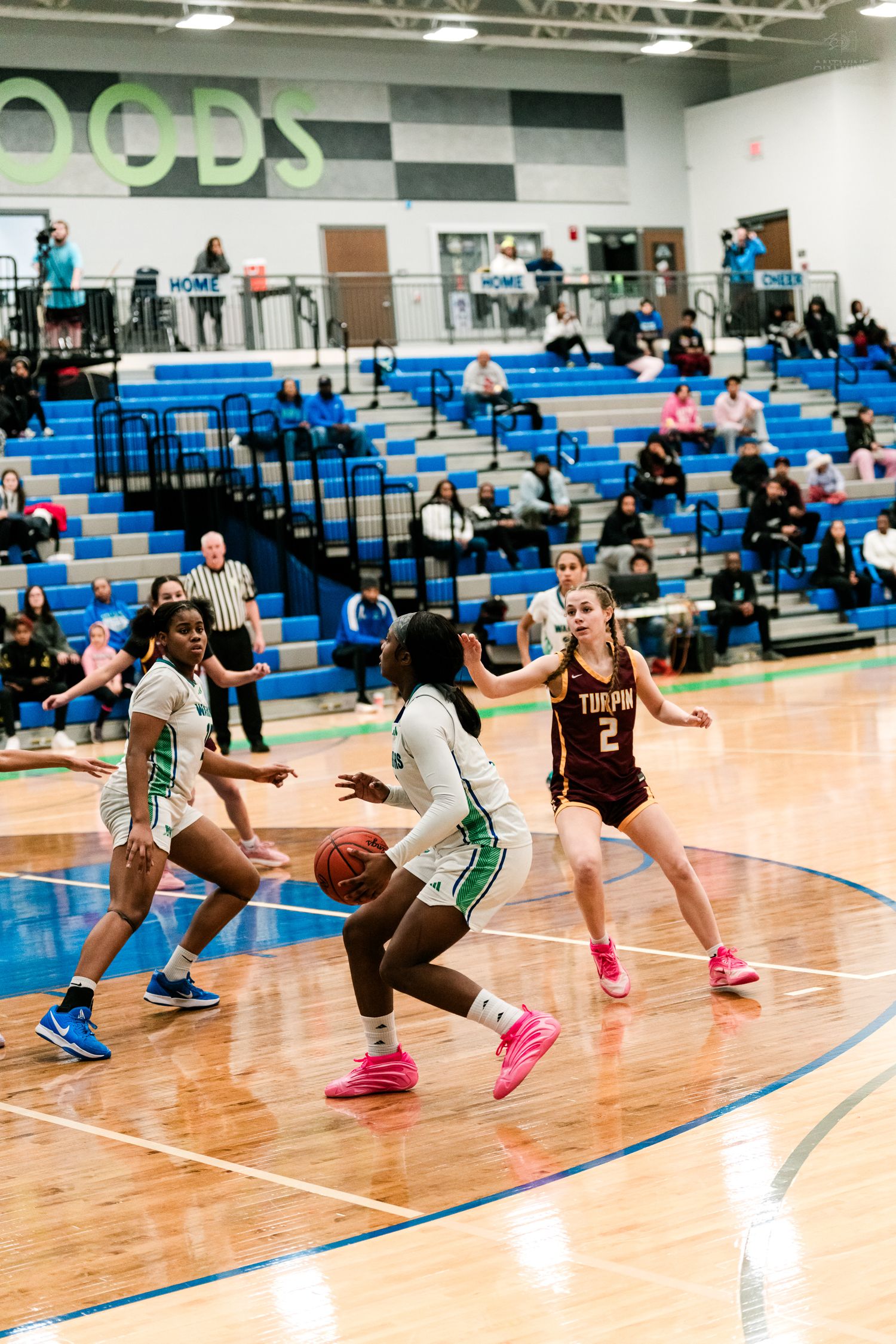 Girls basketball players in white Warriors uniforms drive toward the basket while maroon-uniformed Turpin defenders guard the lane.