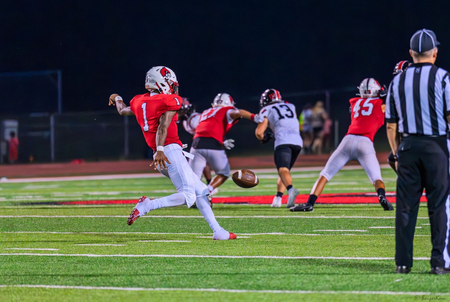 Colerain football player number 1 in red throws a pass during a night game.