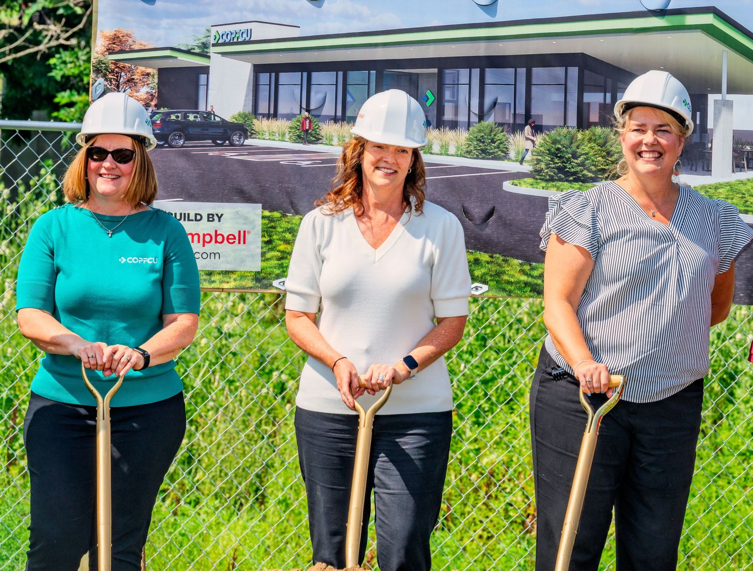 Three women in hard hats holding golden shovels at COPCU Hamilton branch groundbreaking ceremony outdoors.
