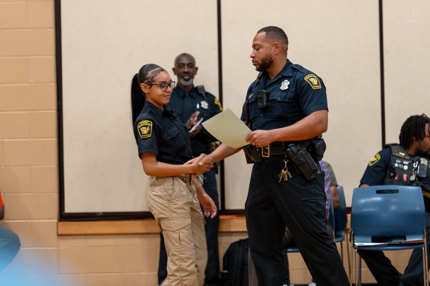Two police officers in uniform reviewing documents at an indoor community event.