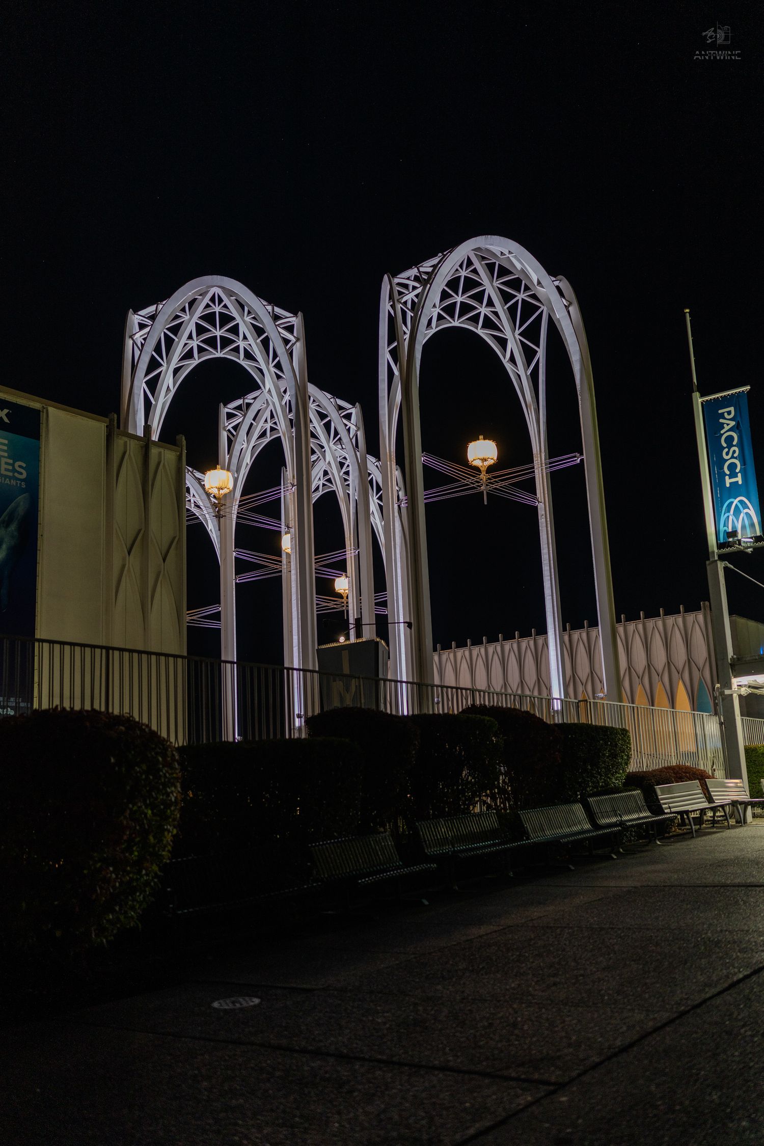 Illuminated white Gothic arch sculptures outside PACSCI science center at night with lantern lights.