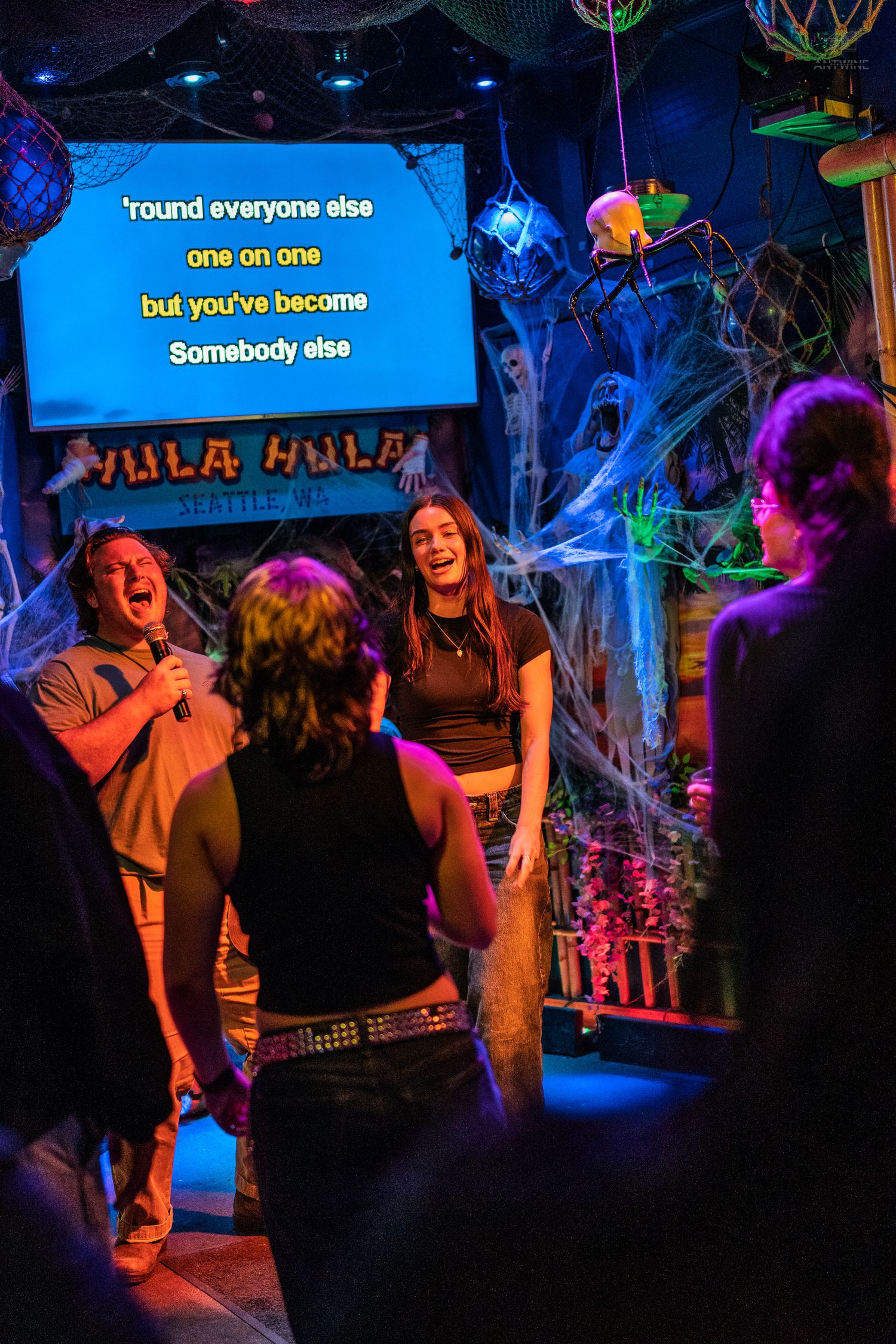 Two people singing karaoke together at Halloween-themed Hula Hula bar in Seattle.