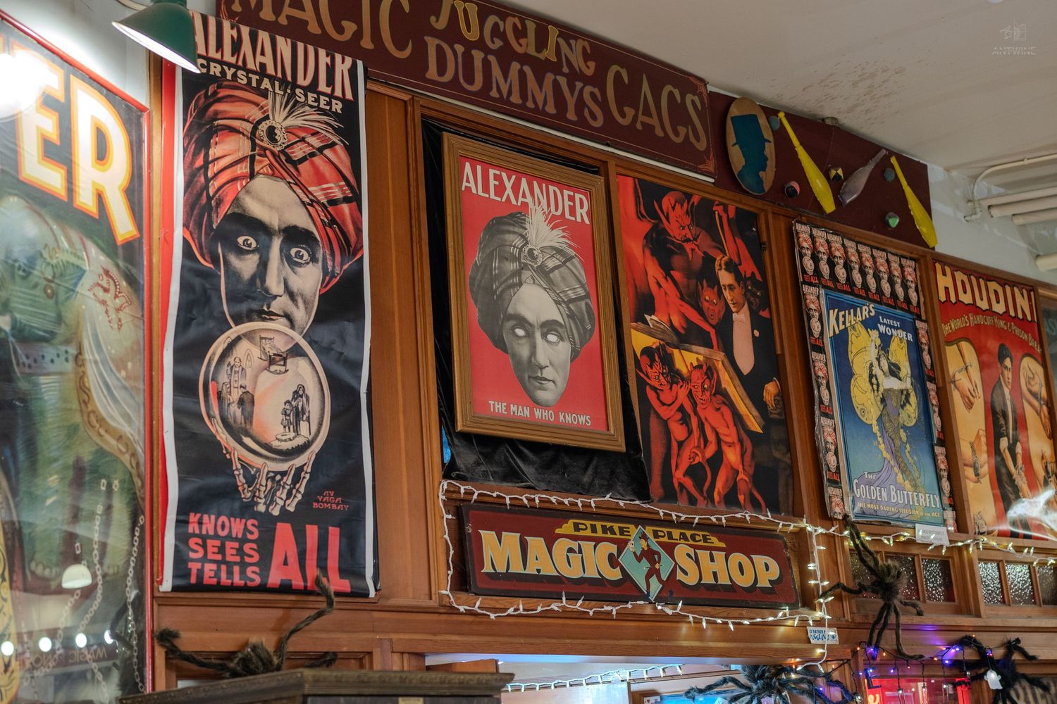 Vintage magic show posters featuring Alexander and Houdini displayed in a colorful magic shop.
