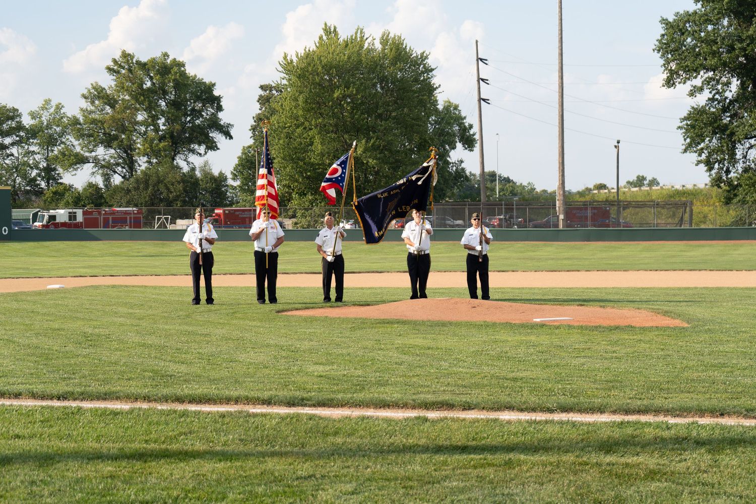 Color guard presenting American and Ohio flags on a baseball field during a pre-game ceremony on a sunny day.