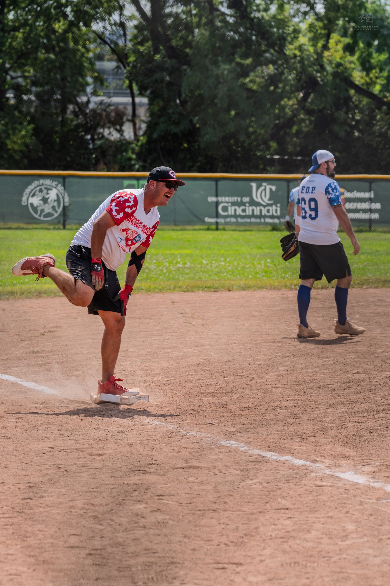 Baseball player running bases during a Battle of the Badges charity softball game on a sunny day.