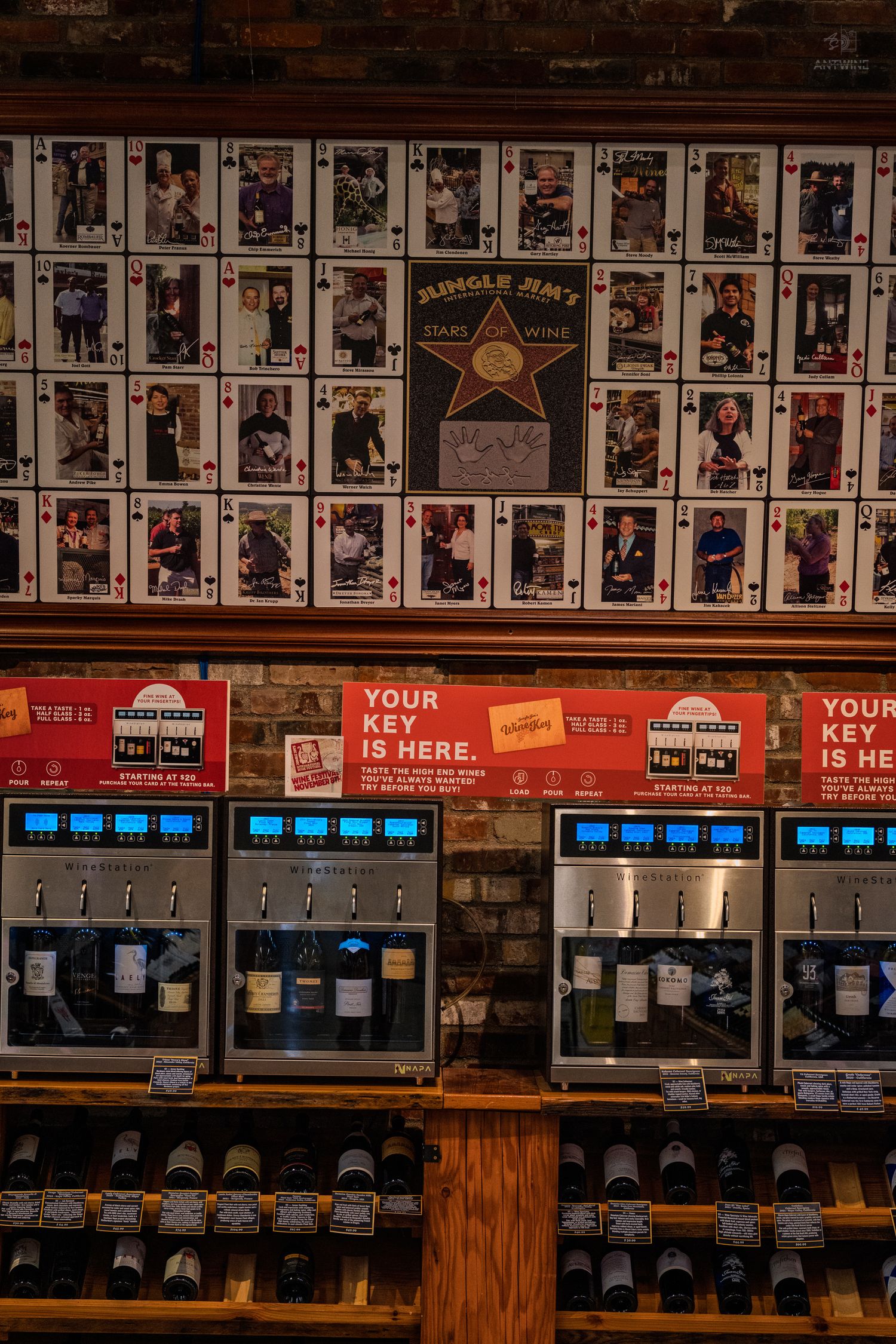 Wine dispensing machines below a wall of playing card-style celebrity photos at Jungle Jim's market.