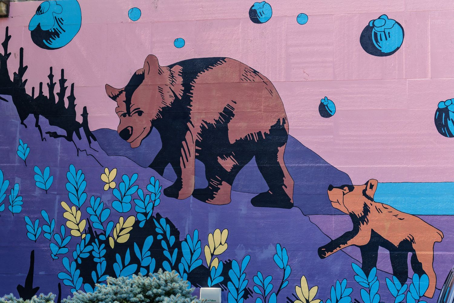 Colorful street mural featuring two brown bears walking among blue plants on a pink and purple background.