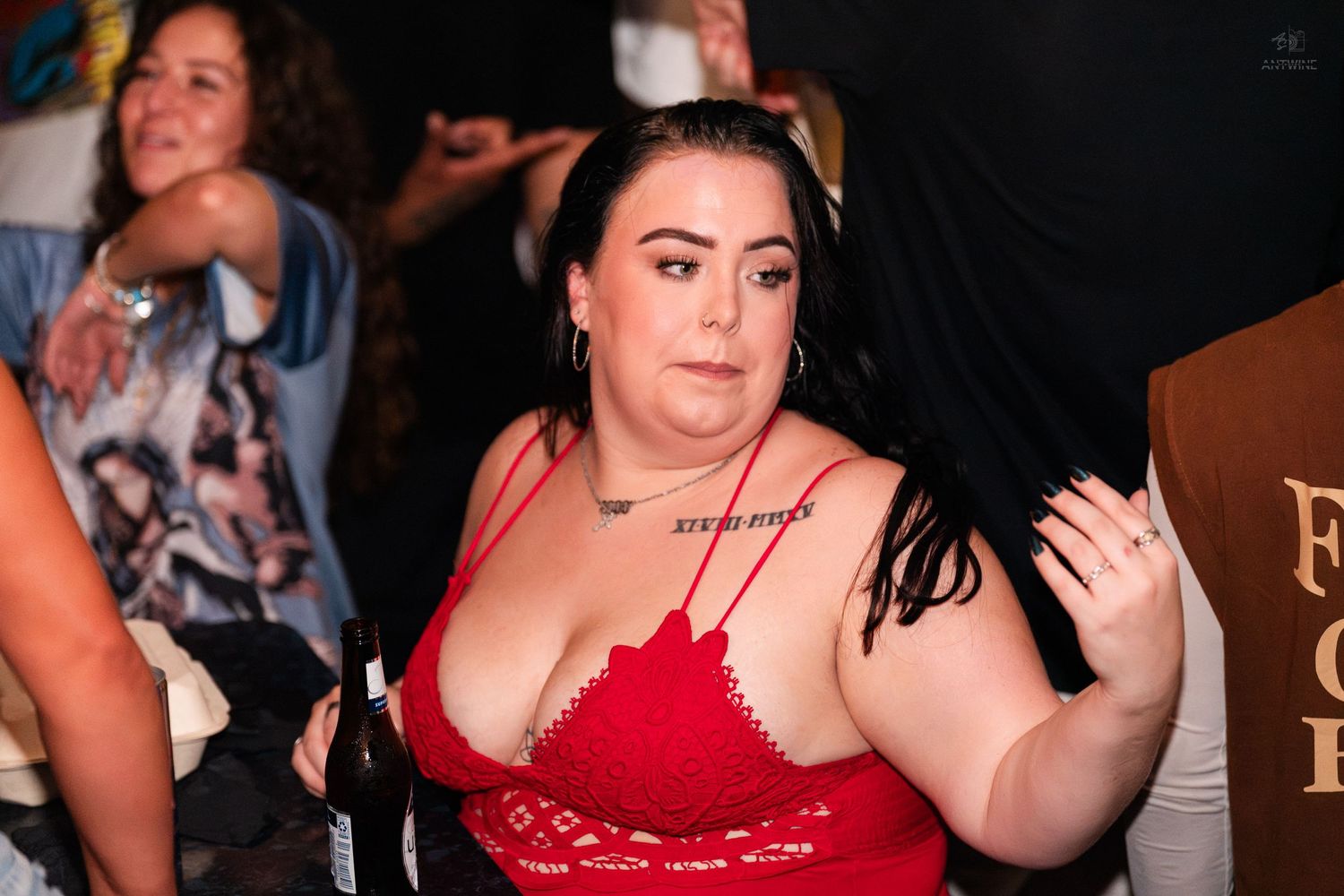 Woman in red lace top posing confidently at a crowded nightclub event.