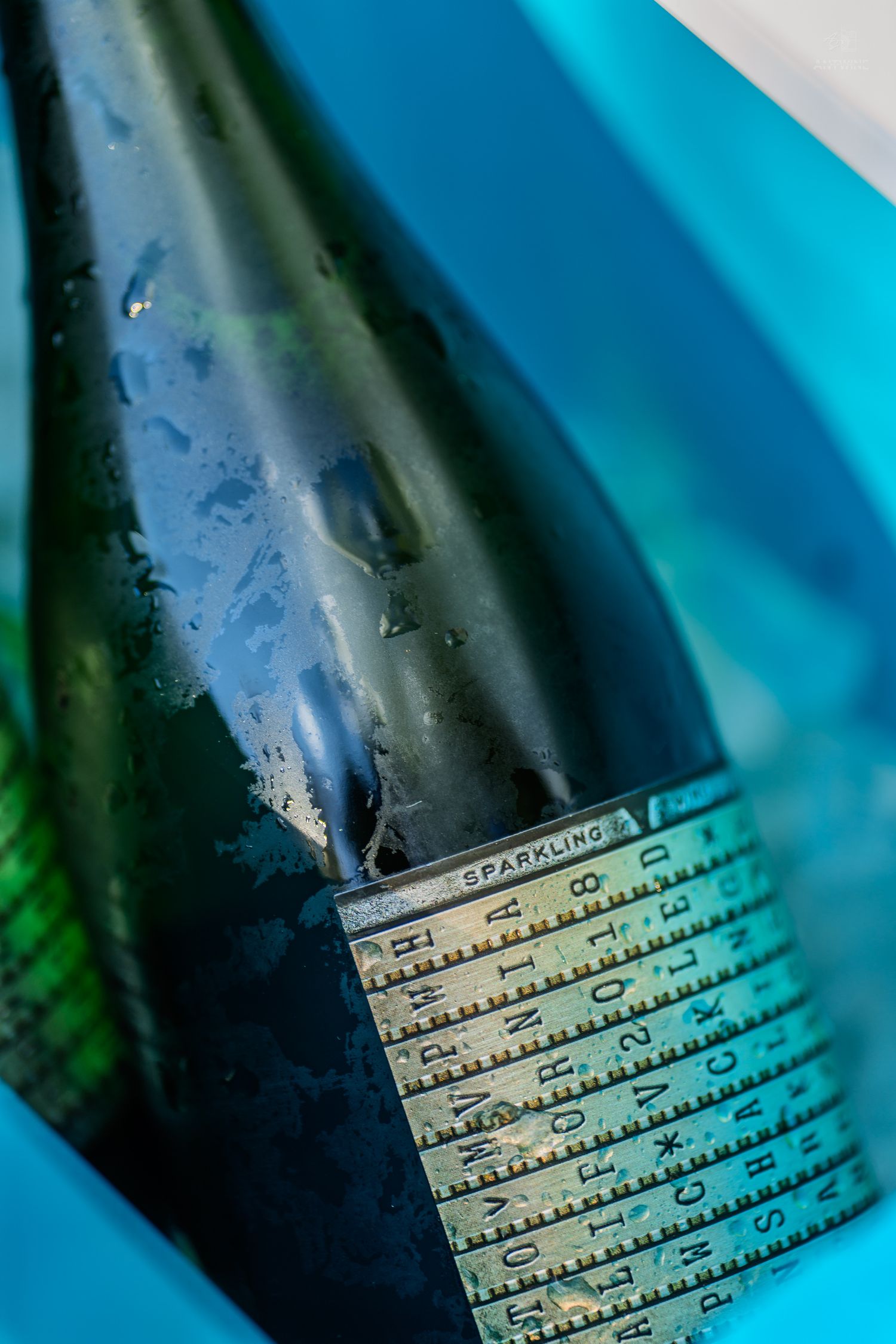 Close-up of a sparkling wine bottle chilling in a blue ice bucket with condensation droplets.
