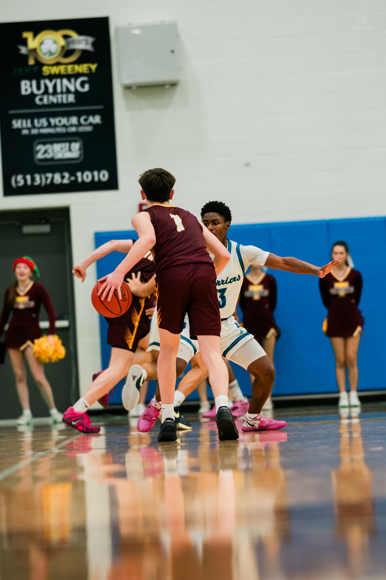 Basketball player wearing maroon jersey number 1 dribbles while being defended by a Warriors player.