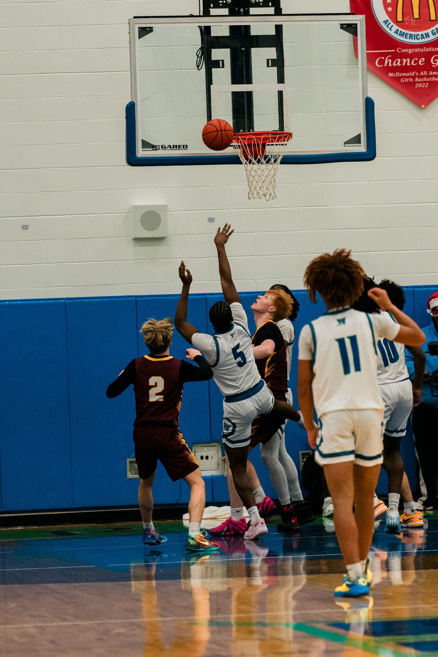 High school basketball players battle for rebound near hoop during Turpin vs Warriors game.