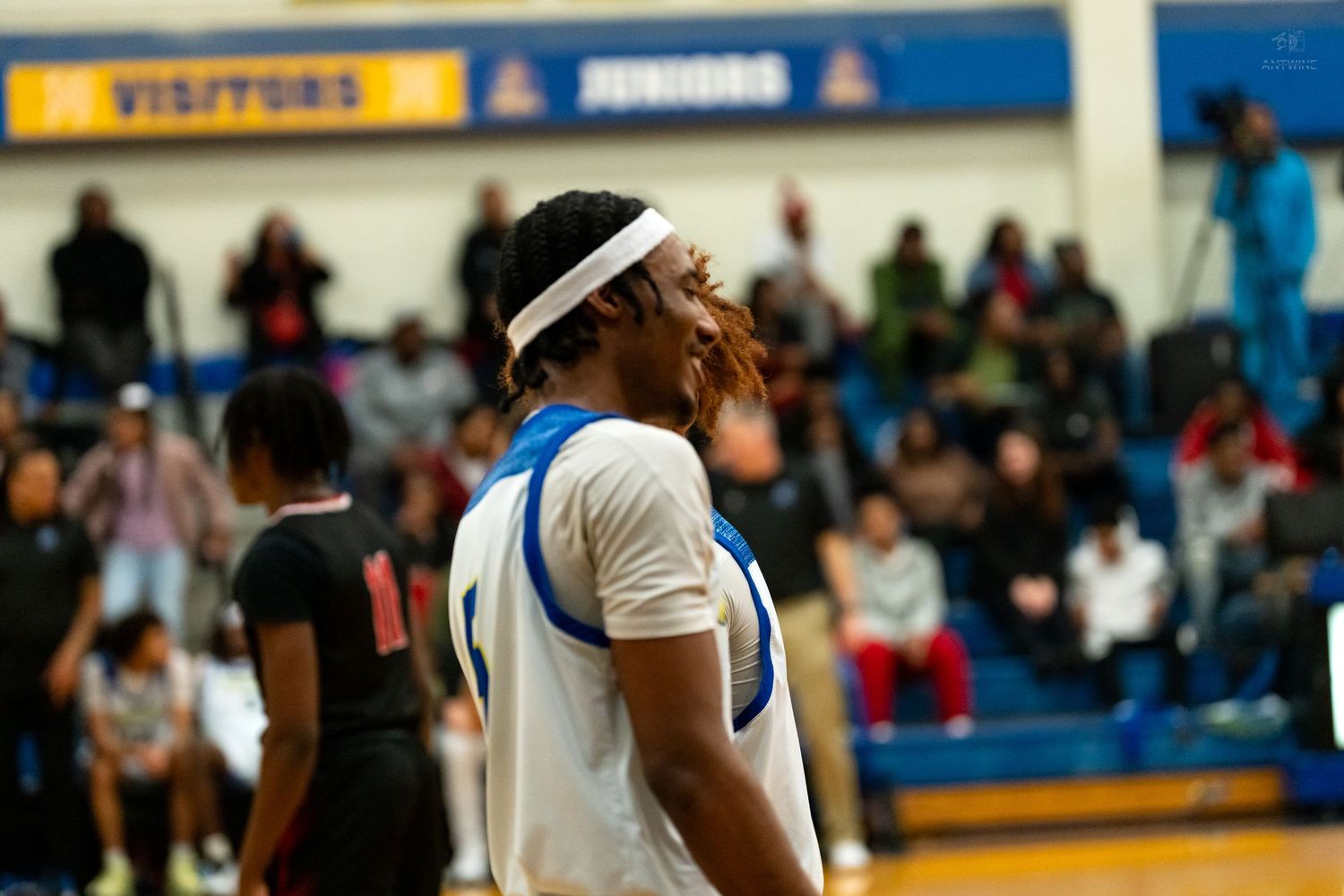 High school basketball player in white uniform with headband looks up during an intense game moment.
