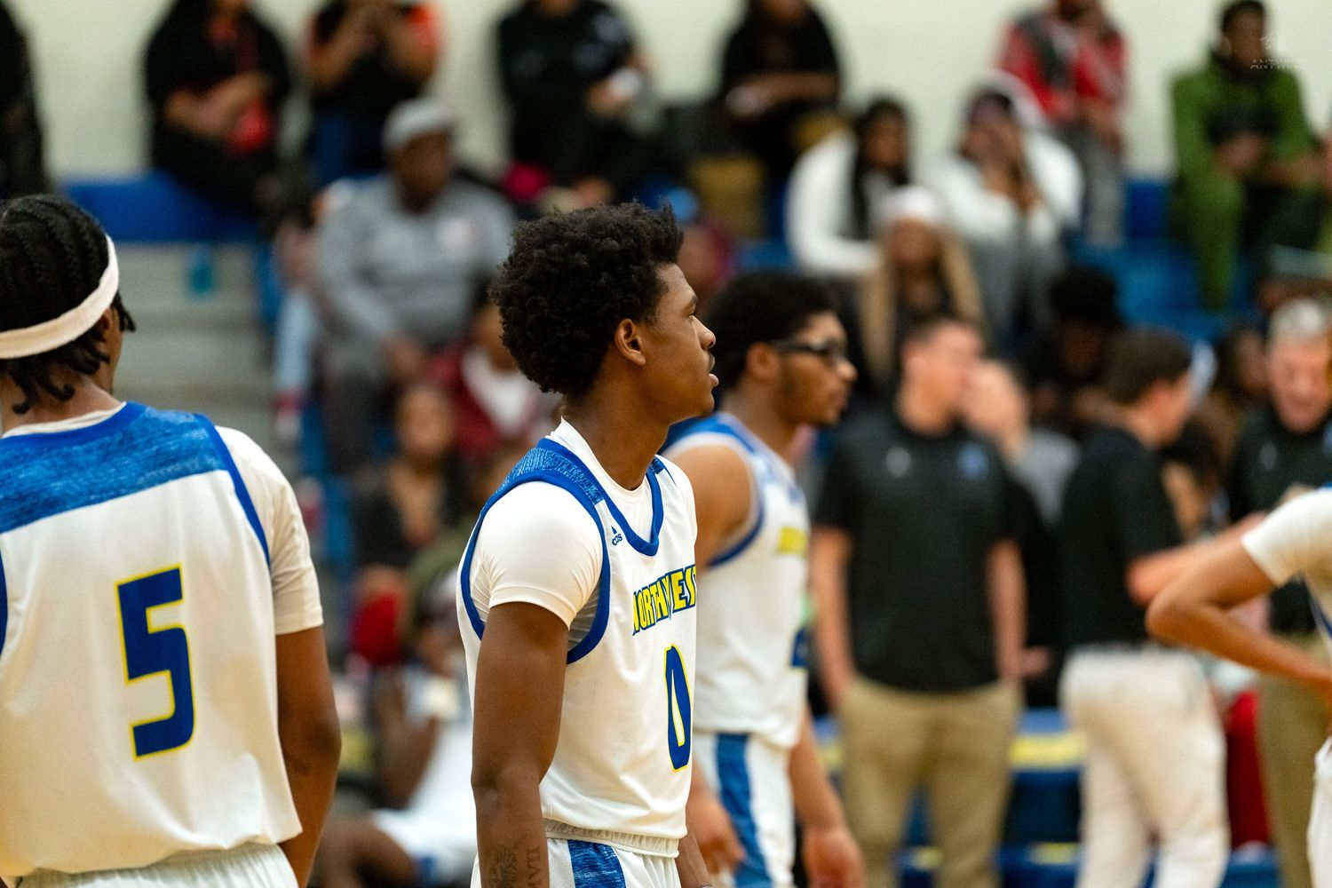 High school basketball players in blue uniforms stand on court with number 5 and 0 visible during game.