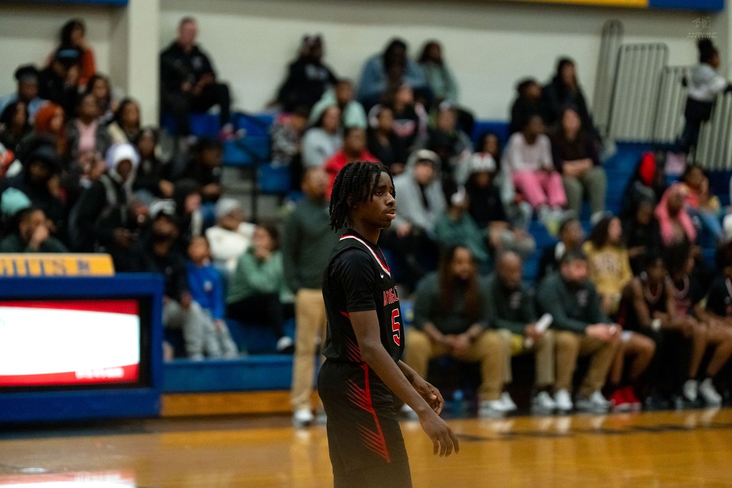 Basketball player in black and orange uniform stands on court during Knights home game.