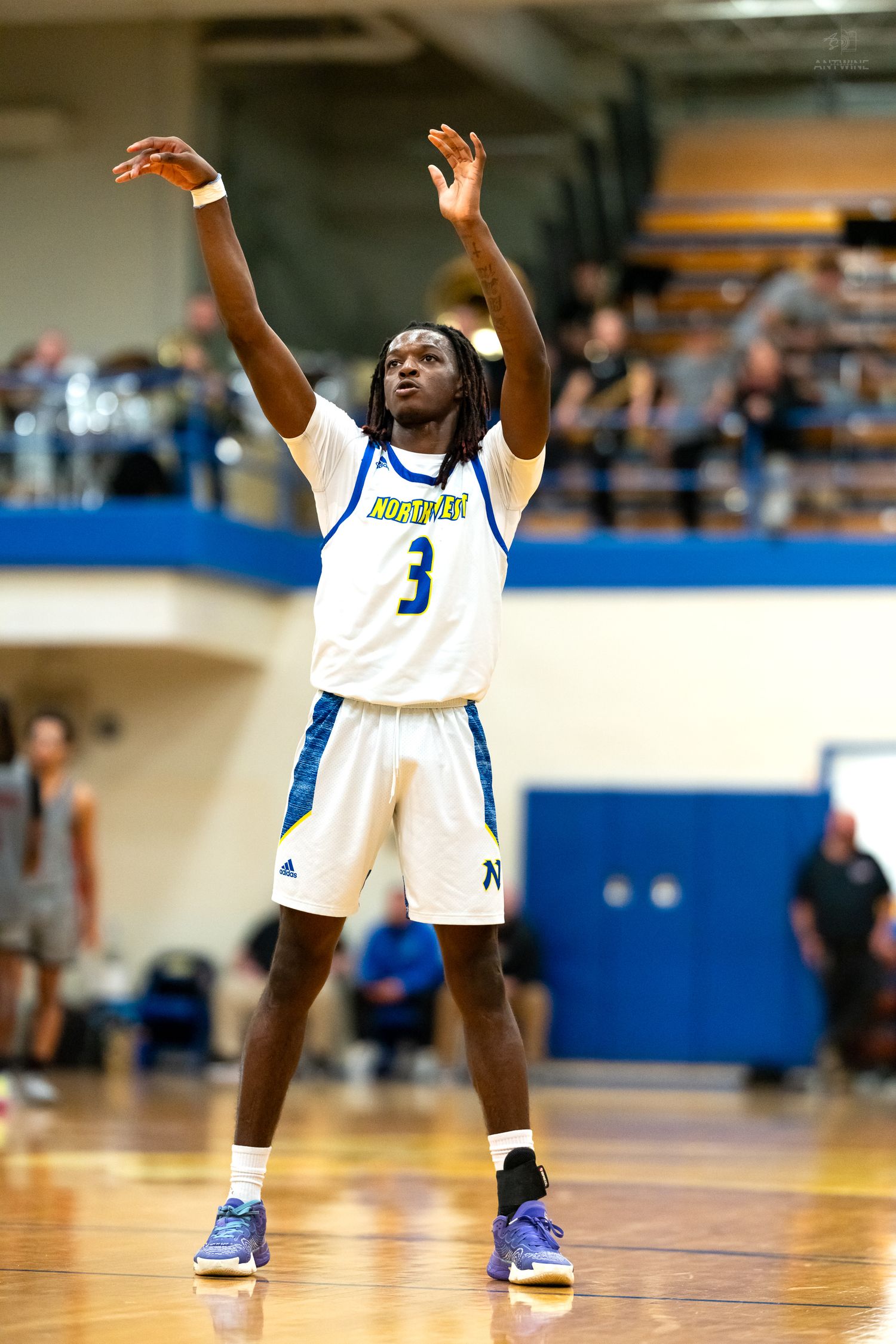 Basketball player #3 in white Northgate jersey raises hands after shot during indoor game.