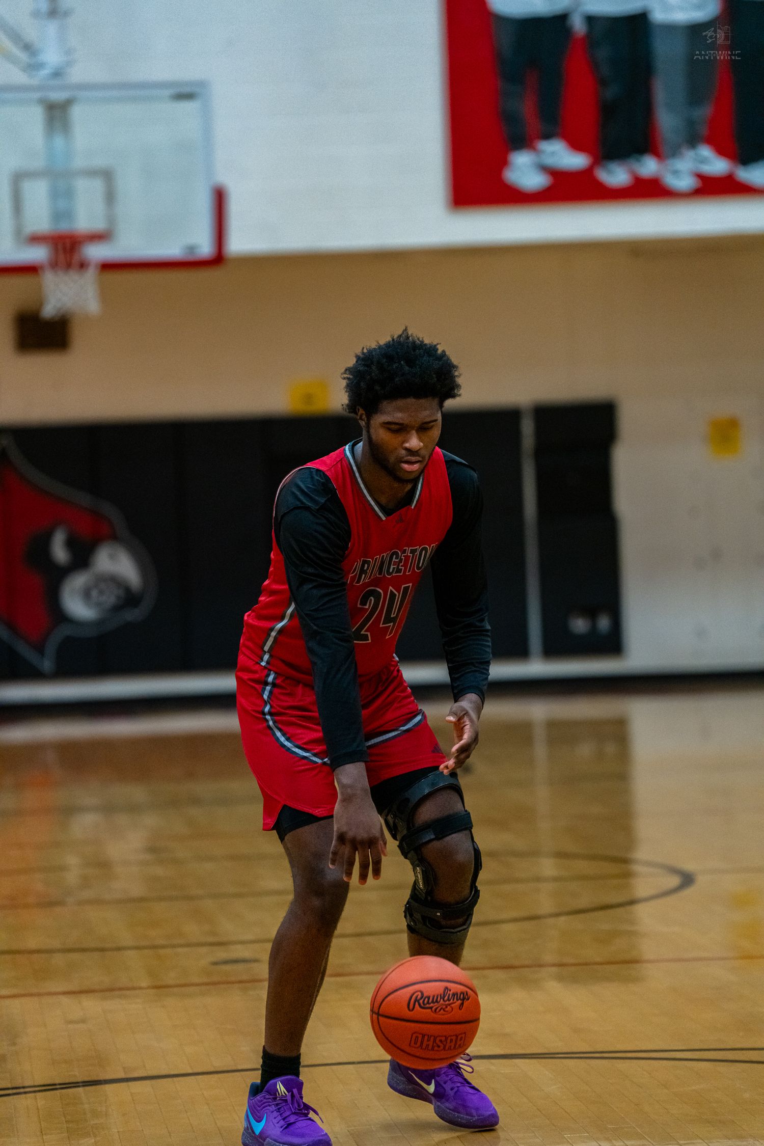 A Princeton High School basketball player number 20 dribbles the ball during a game on a hardwood court.