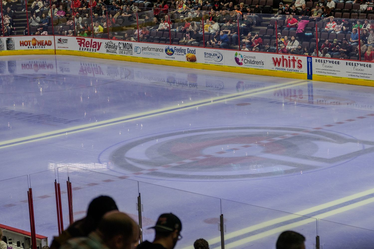 A wide view of a hockey rink showing the team logo at center ice with spectators filling the arena stands.