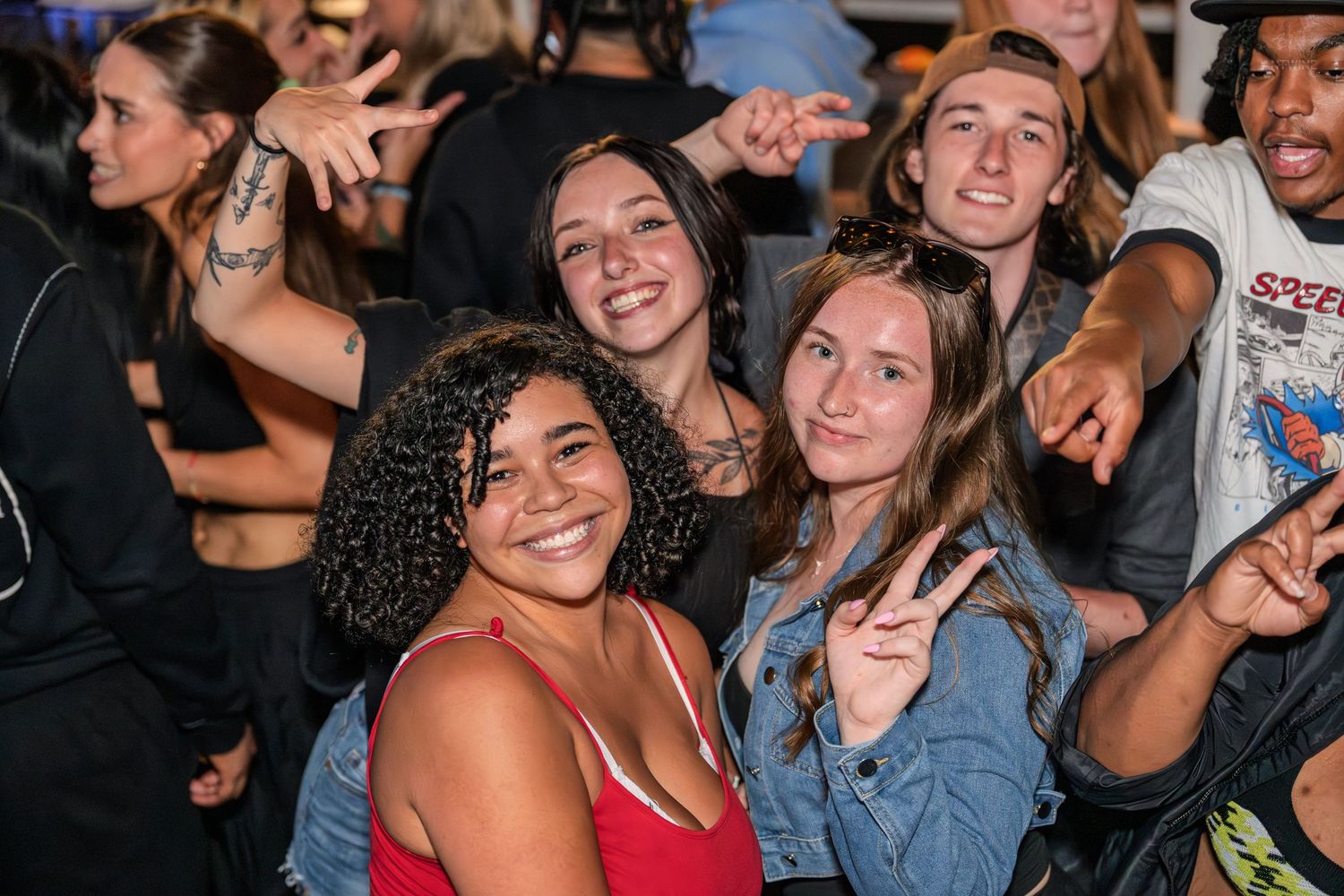 Group of smiling young friends posing together at a nighttime outdoor concert event.