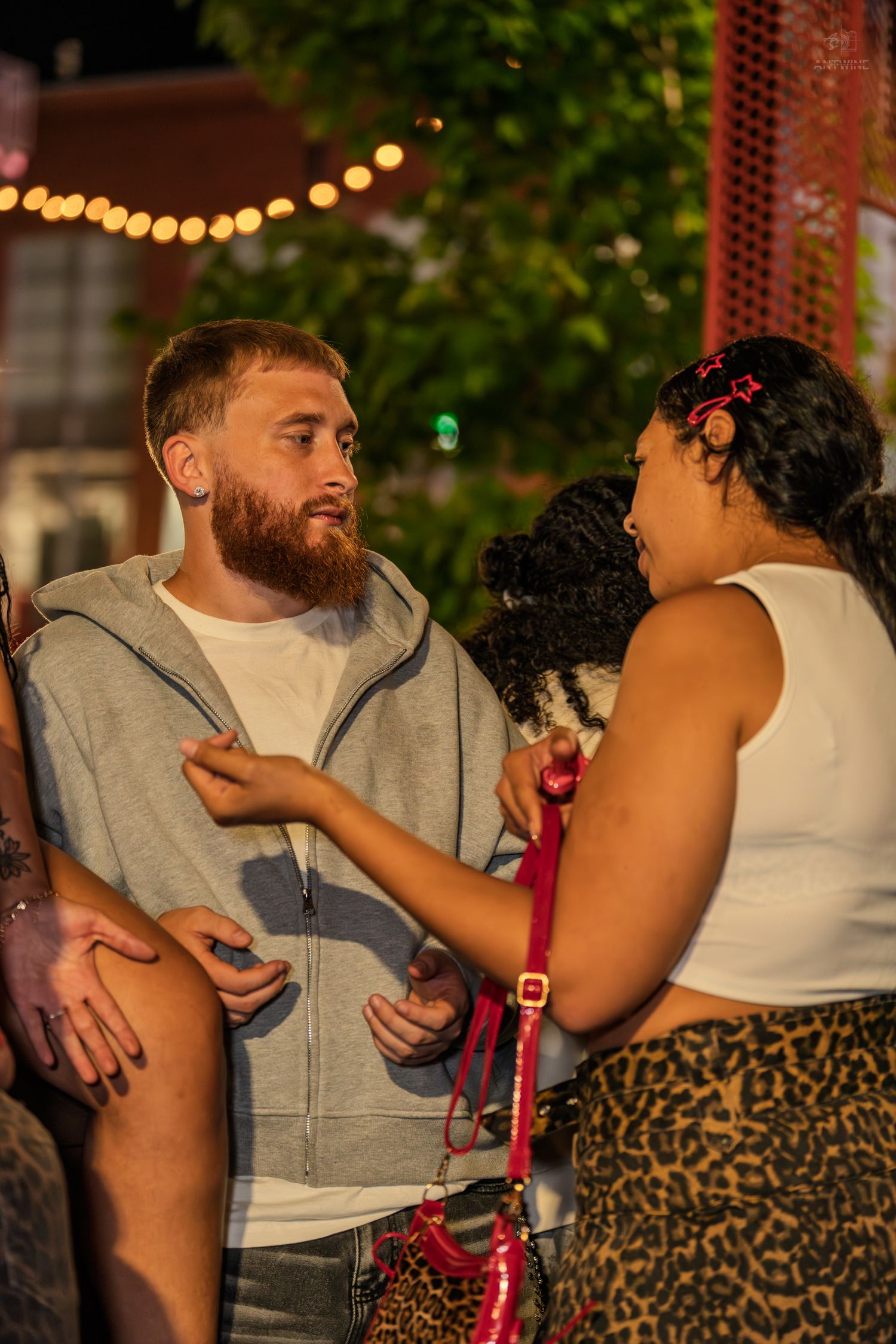 Bearded man and woman having a conversation at an outdoor nighttime social event.