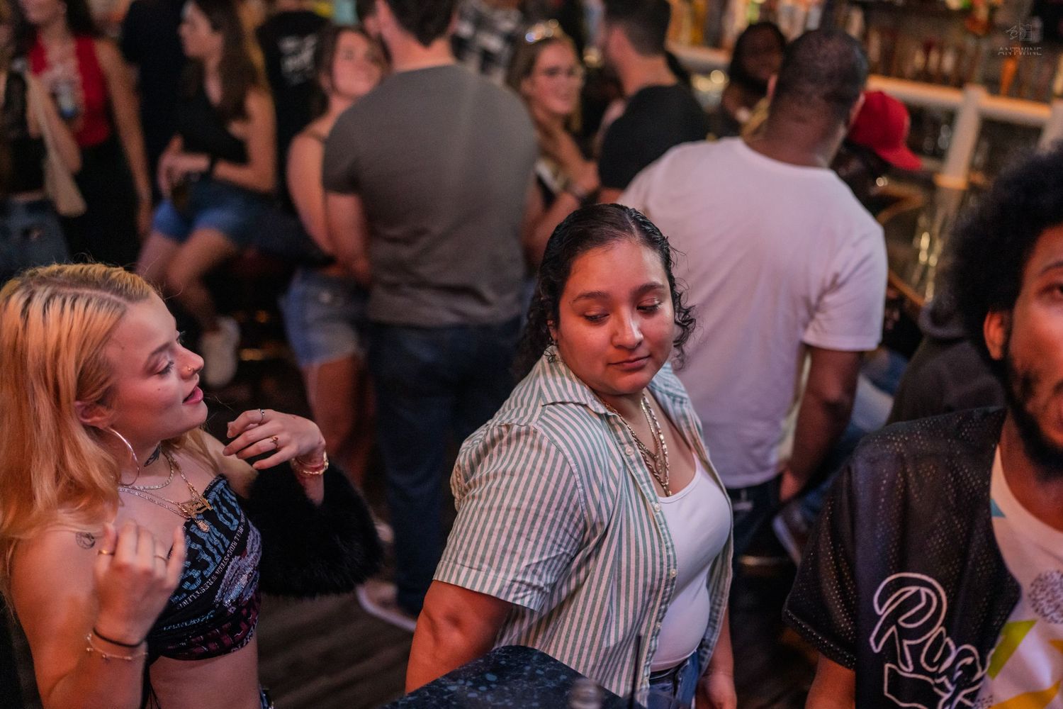 Young women dancing and socializing on a busy nightclub dance floor.