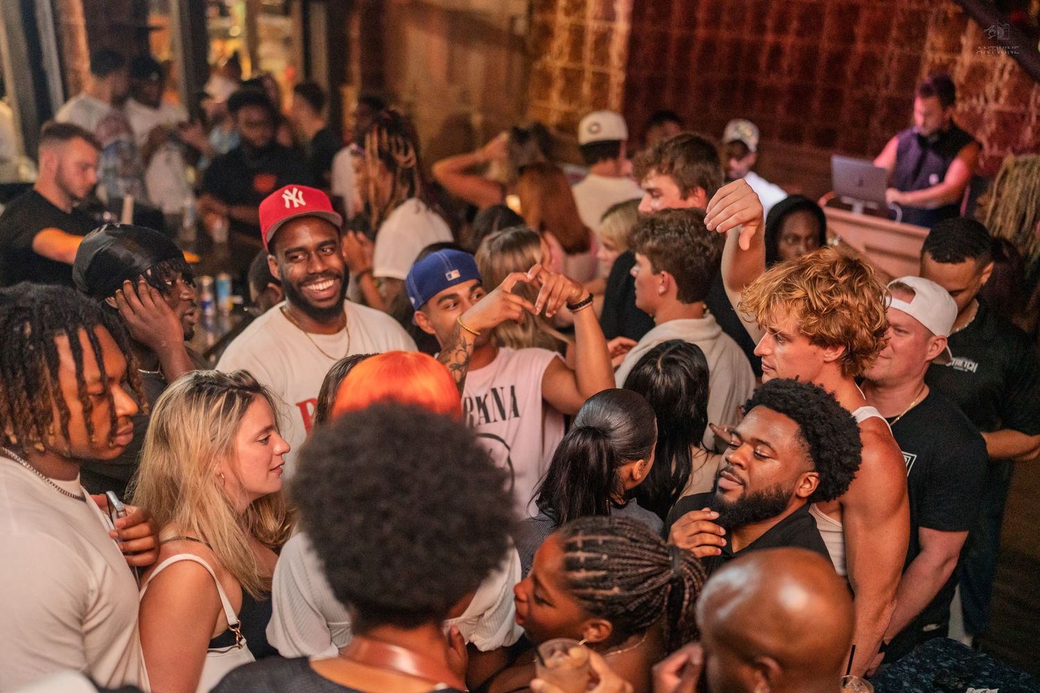 Large diverse crowd of people socializing and having fun at a lively nightclub event.