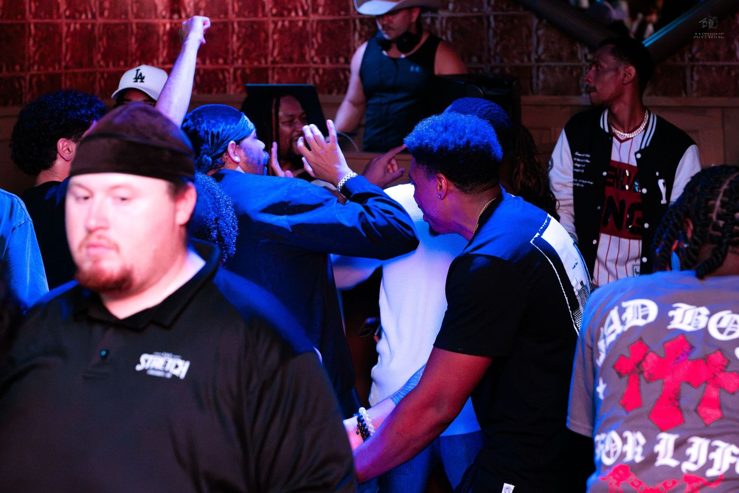 Crowd of people dancing and socializing under blue lights at a nightclub event.