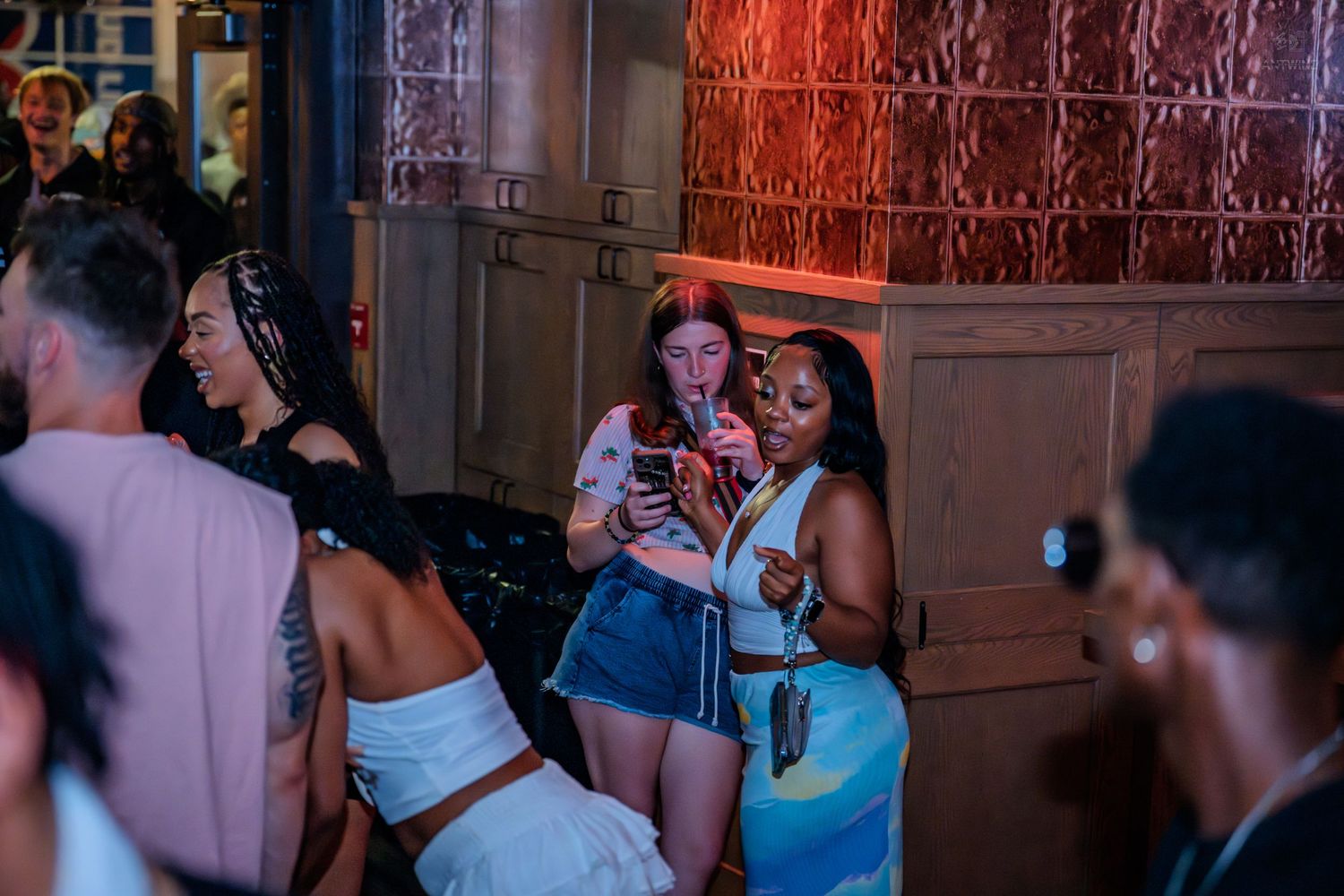 Group of friends socializing and checking phones at a nightclub.