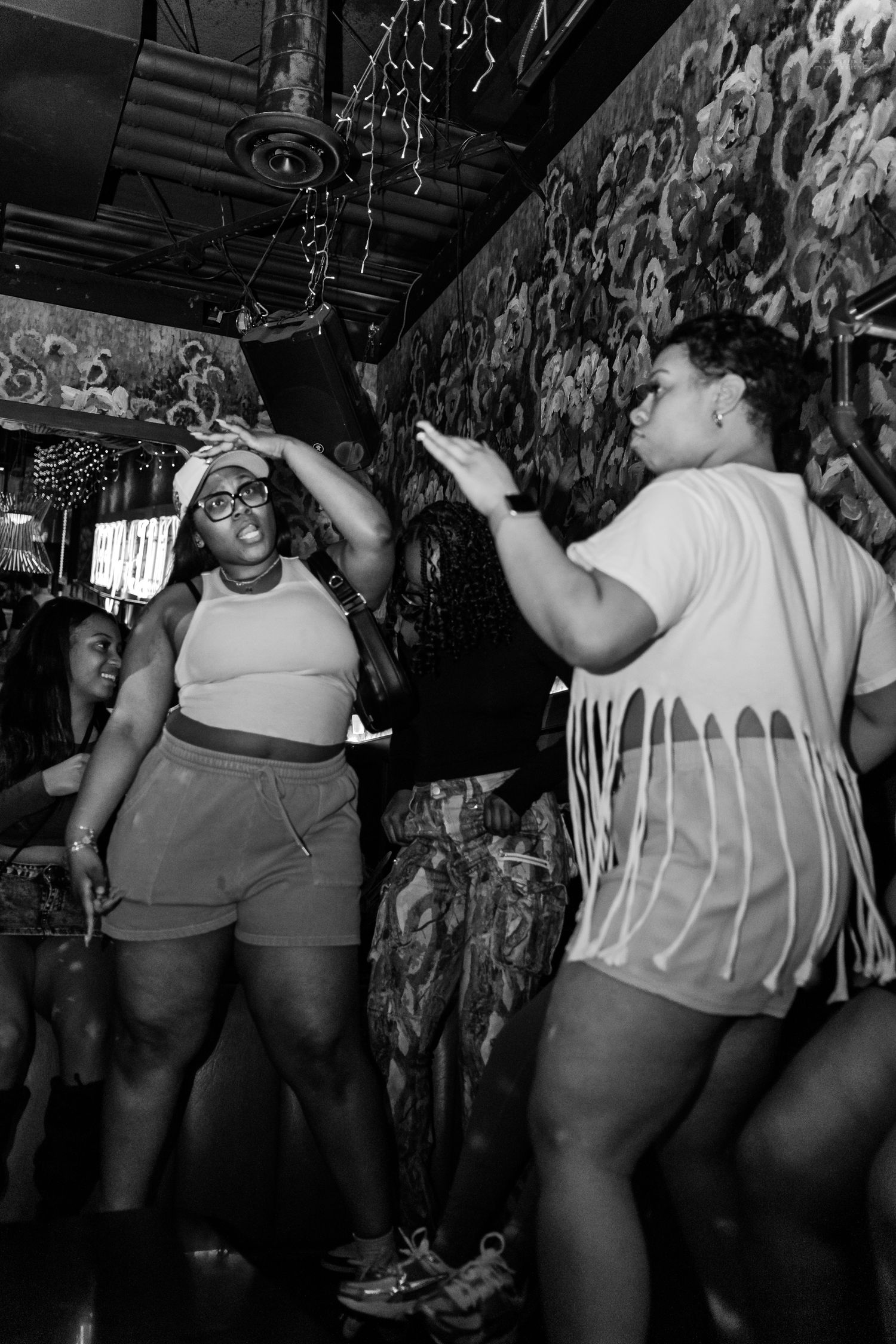 Women dancing joyfully together at a vibrant nightclub party in black and white photo.