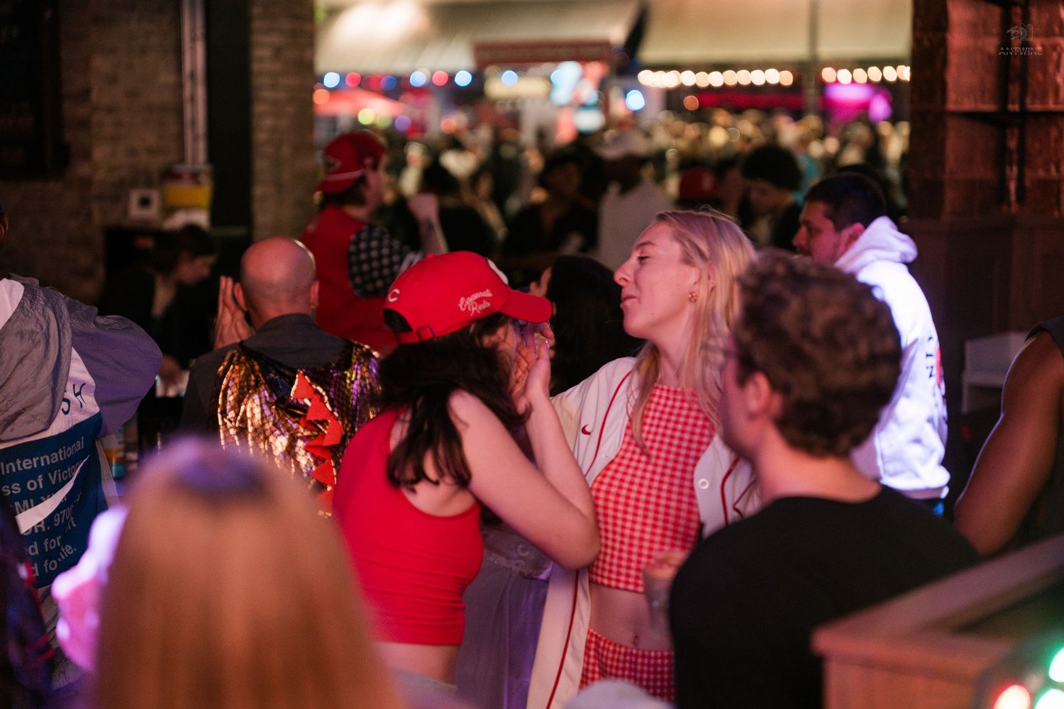 Crowd of people dancing and socializing at a busy indoor nightclub event.