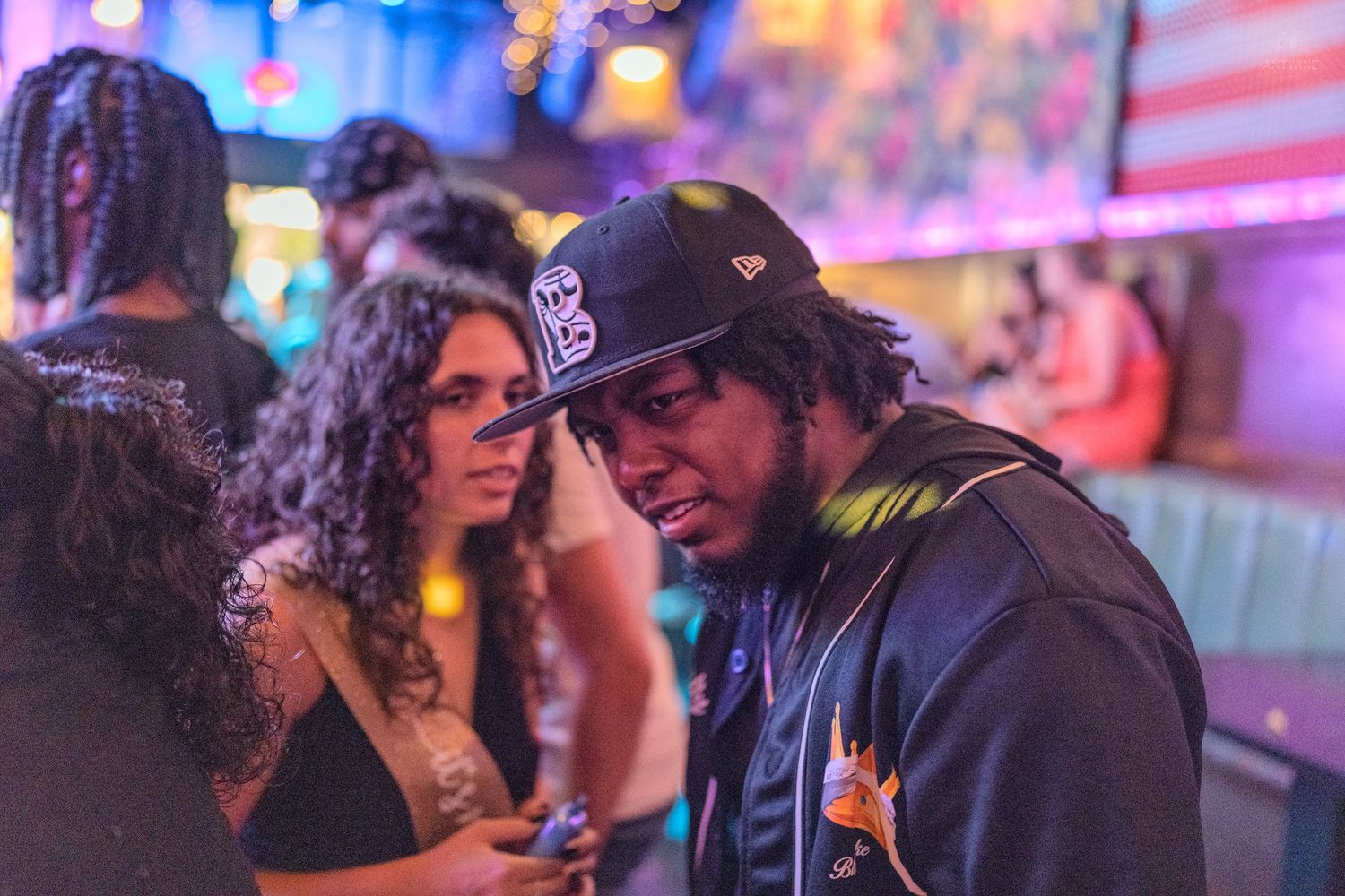 Man and woman having a close conversation in a vibrant neon-lit nightclub.
