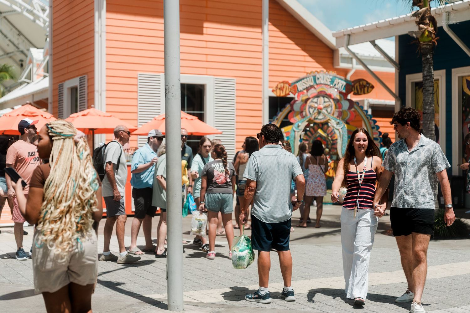 Tourists strolling through a vibrant tropical shopping district with colorful buildings and decor.