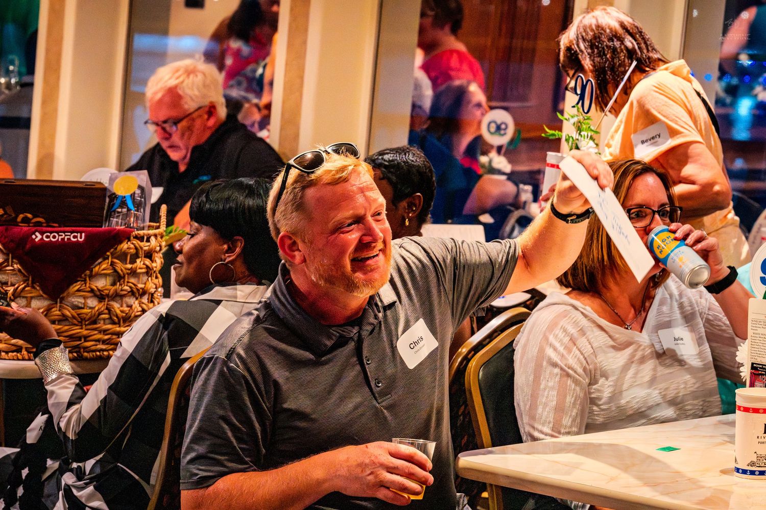Group of adults laughing and socializing at a lively indoor event or party gathering.