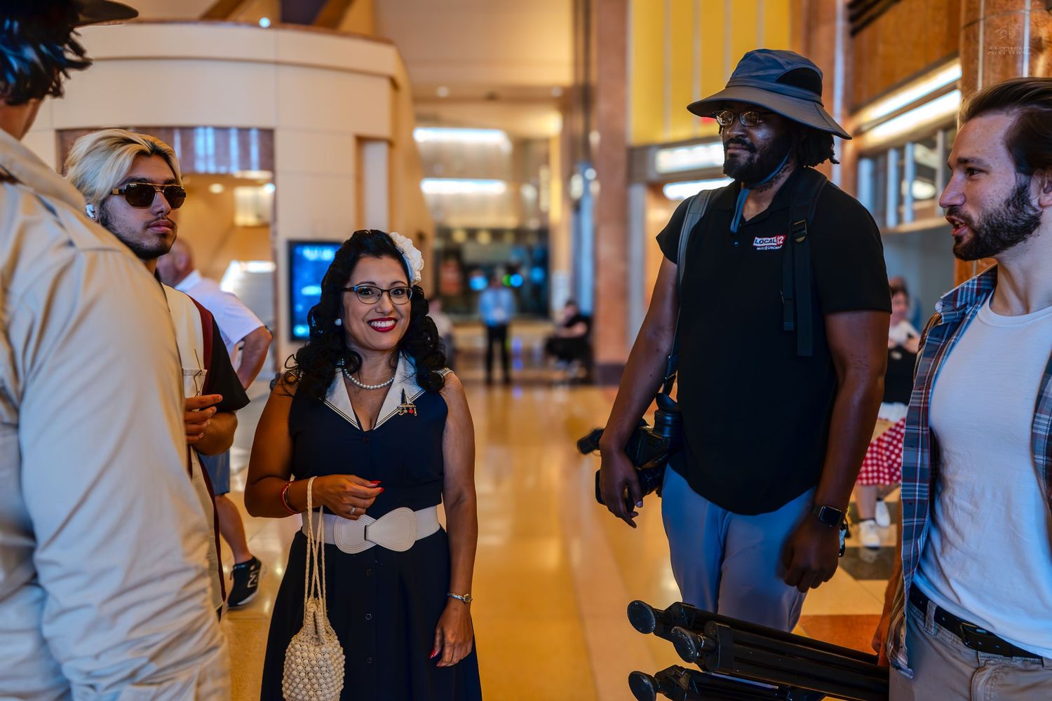 A diverse group of people socializing and laughing in a warmly lit modern building interior.