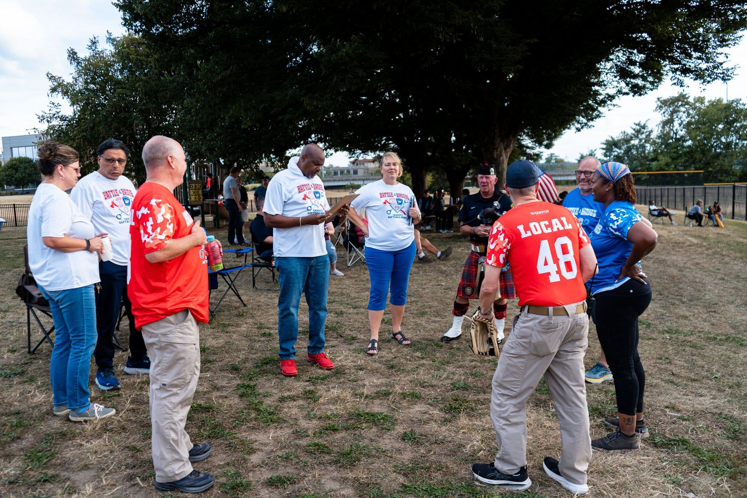 Union members wearing Local 48 shirts gather outdoors in a park for a labor organization meeting or rally.
