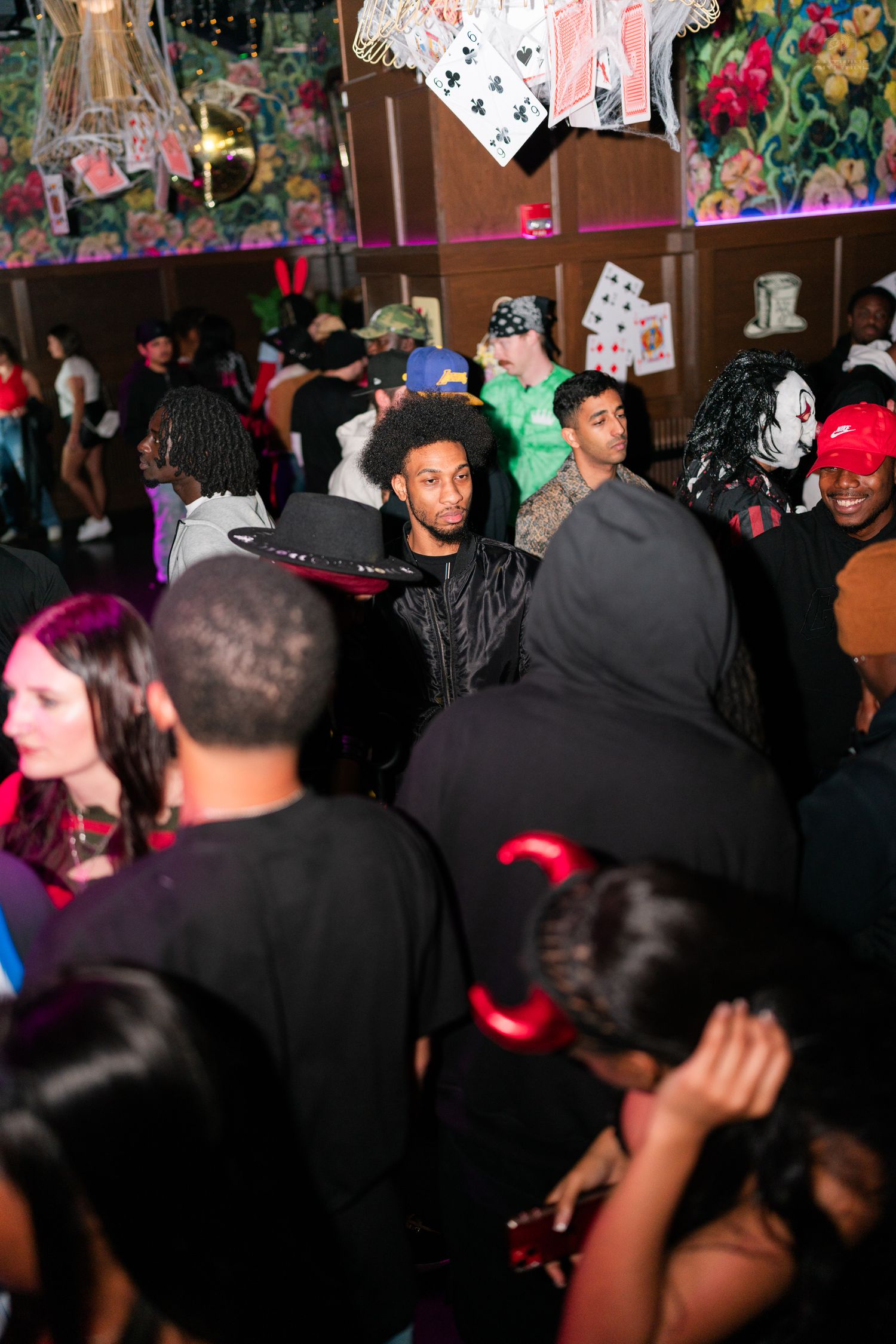 Diverse crowd of people in Halloween costumes dancing at a packed nightclub party.