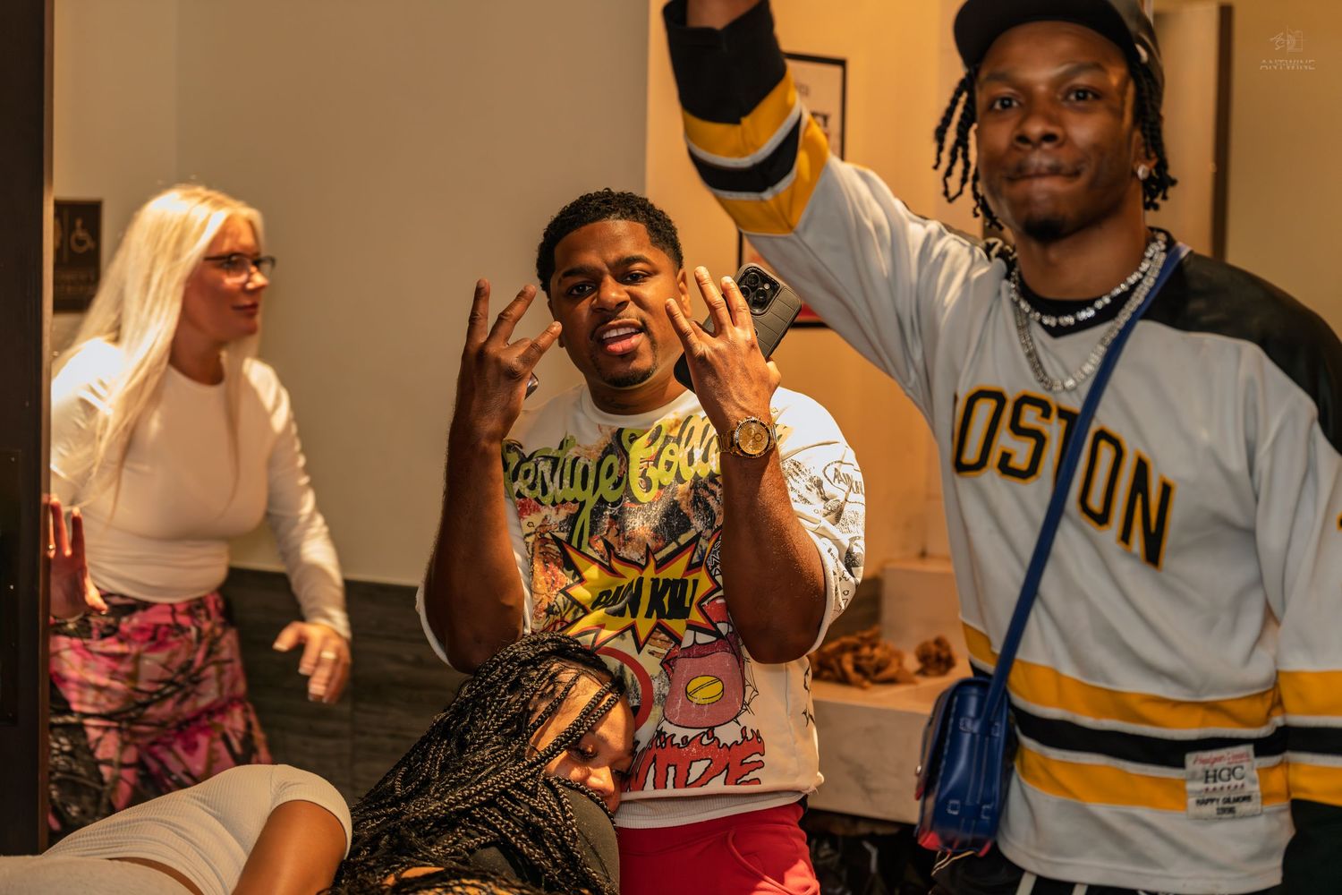 Two young men posing and throwing up hand signs at an indoor party.