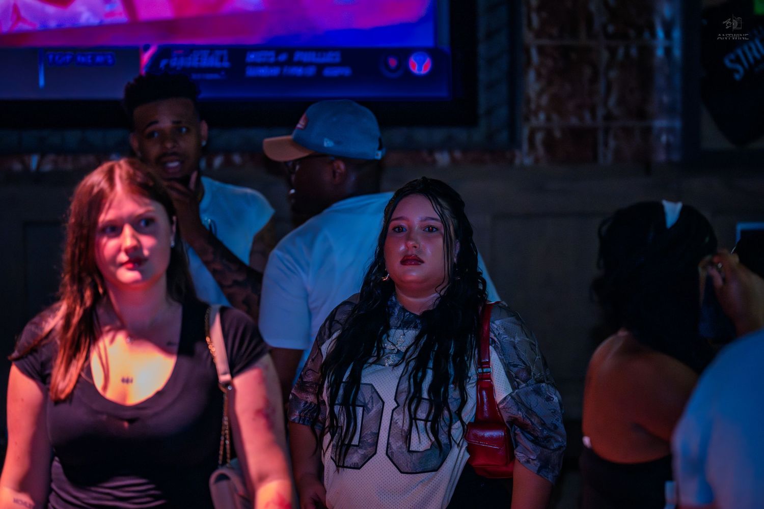 Group of people socializing at a colorful neon-lit nightclub or bar event.