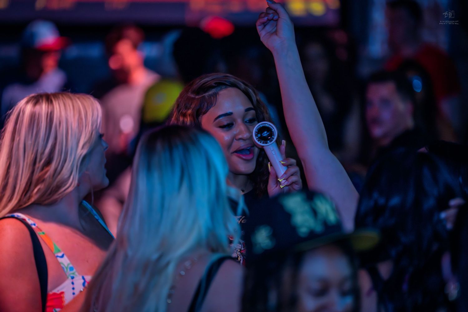 Woman singing into a microphone at a lively nightclub dance party.